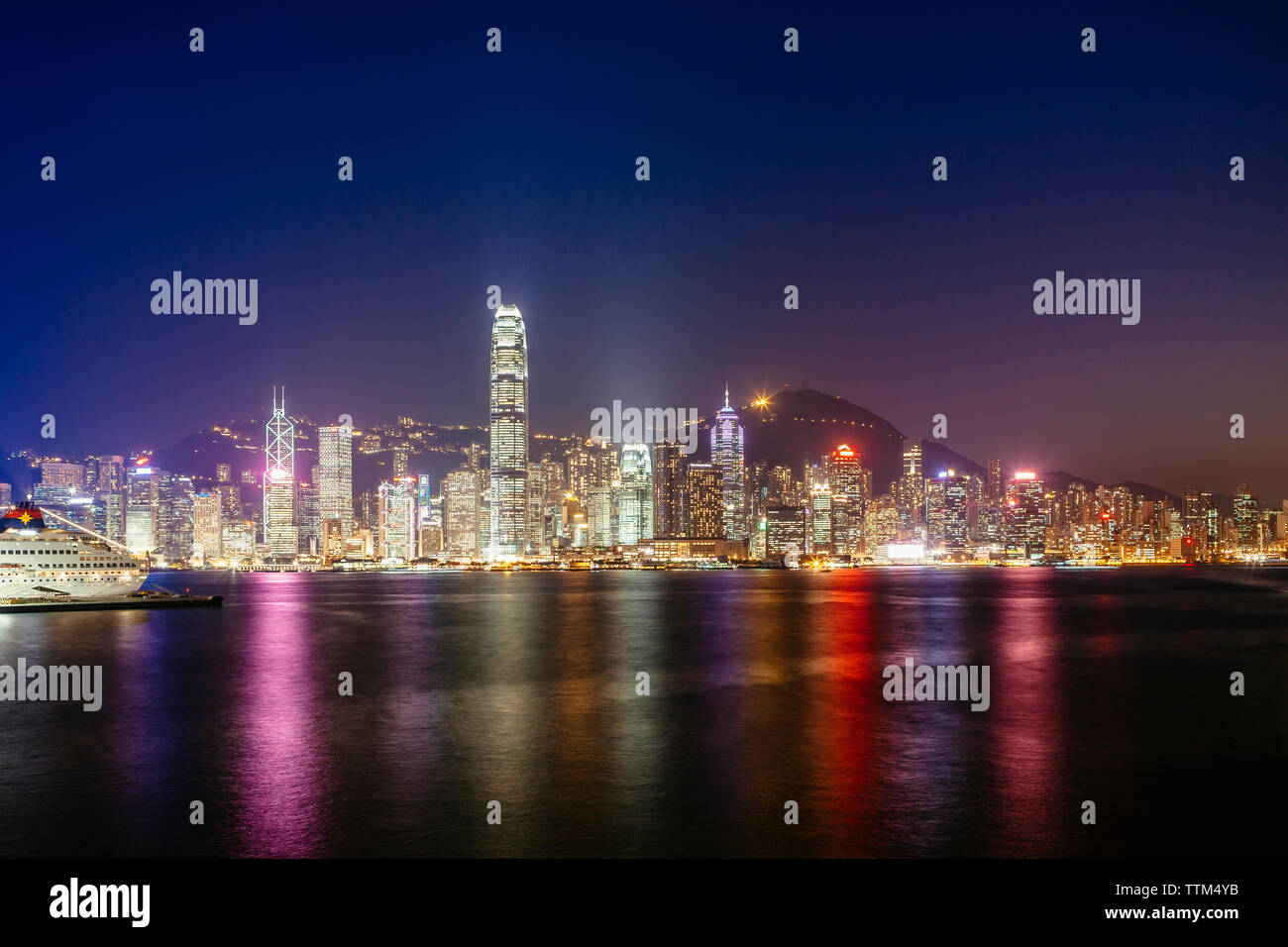 Victoria harbour against illuminated Two International Finance Center and buildings in city at night Stock Photo