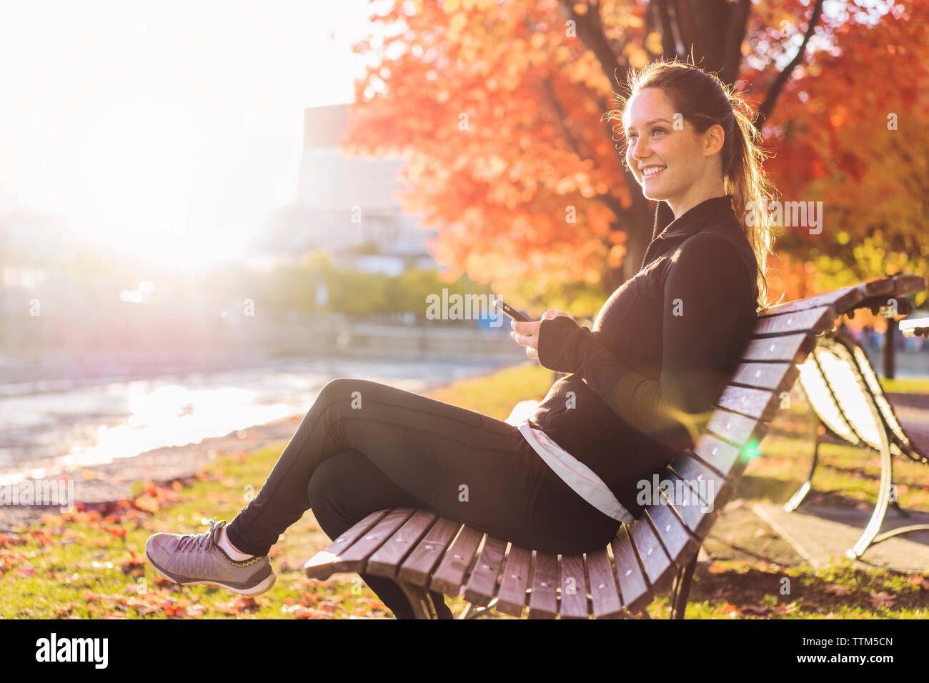 Young woman phone sitting on bench at park hi-res stock photography and ...