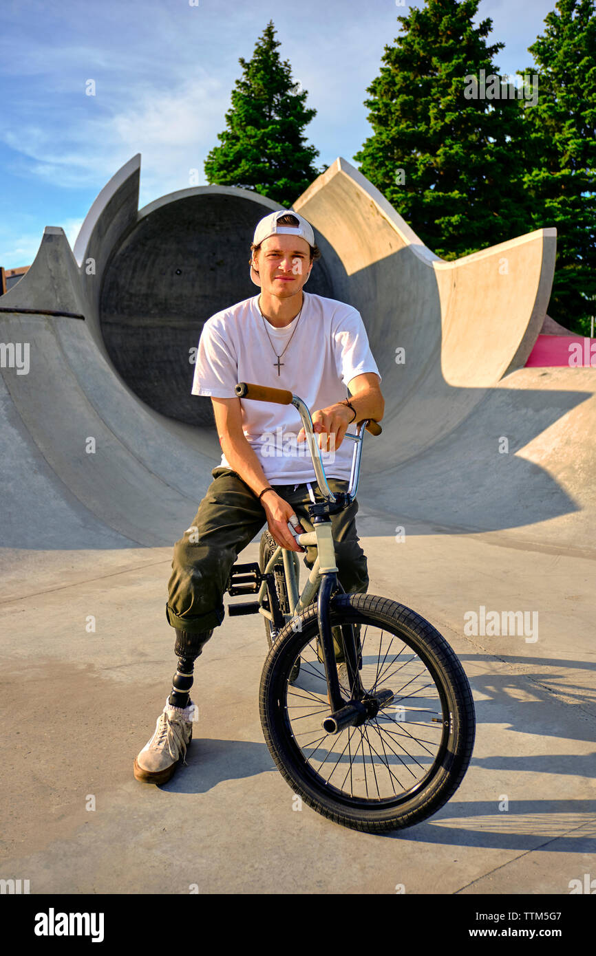 Portrait of BMX rider with prosthetic foot confidently posing on bike at skateboard park Stock Photo