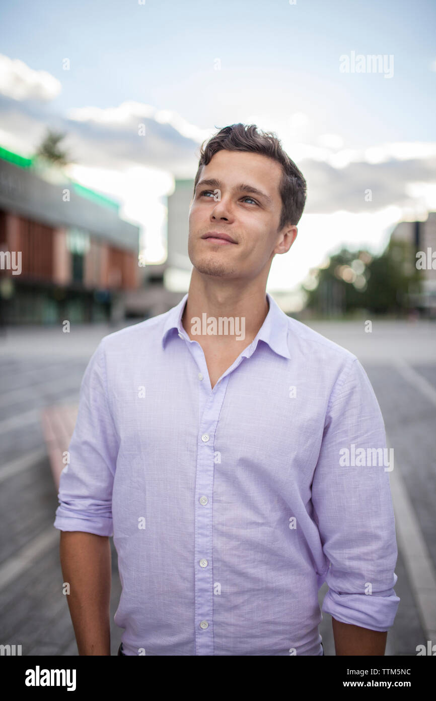 Aspirational portrait of male student looking upwards smiling hopefully in urban area Stock Photo