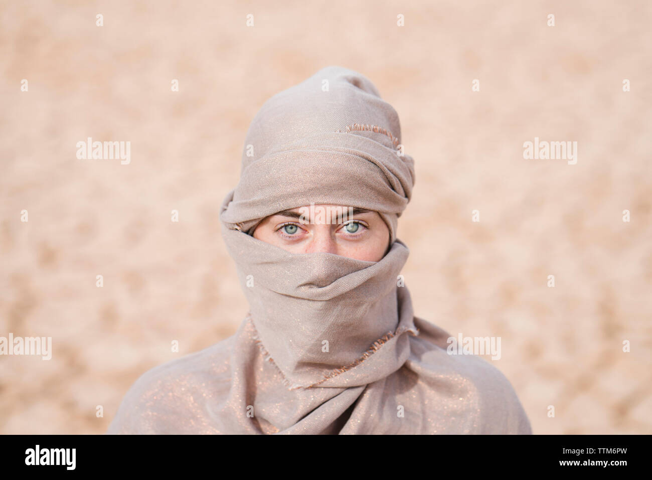 Portrait of woman wearing scarf standing at barren landscape Stock Photo