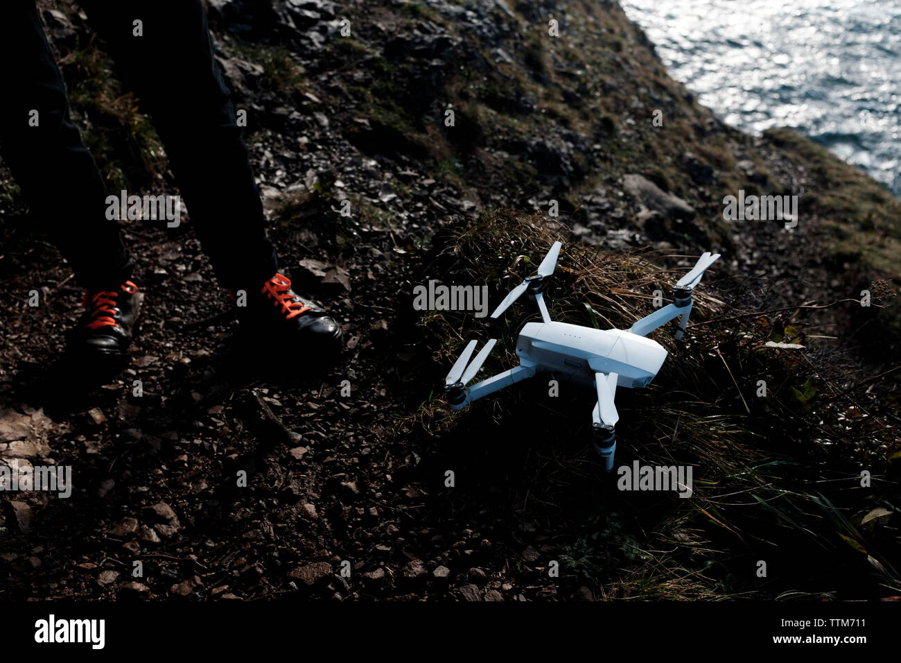 Low section of hiker with drone at beach Stock Photo