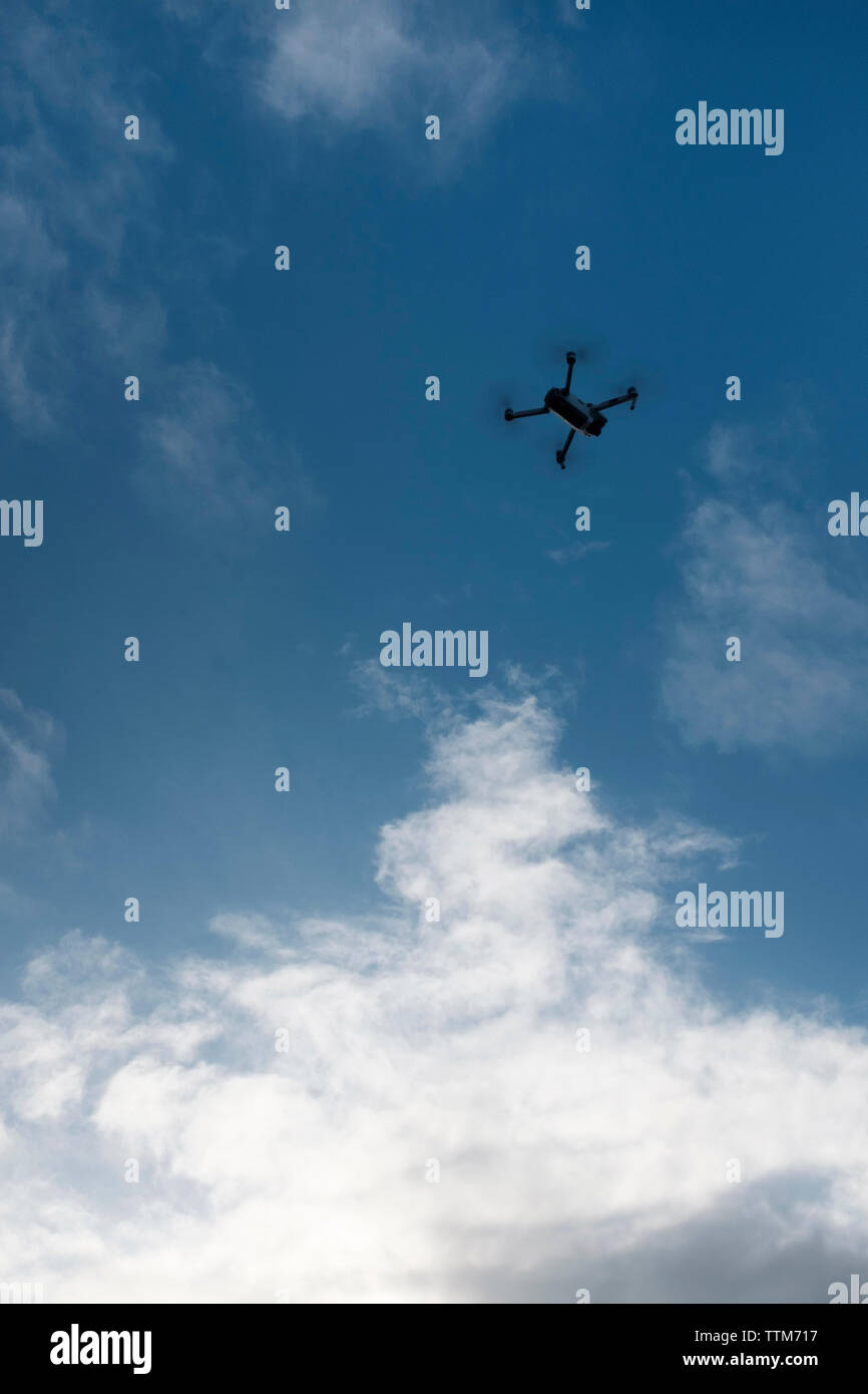Low angle view of drone flying against cloudy sky Stock Photo