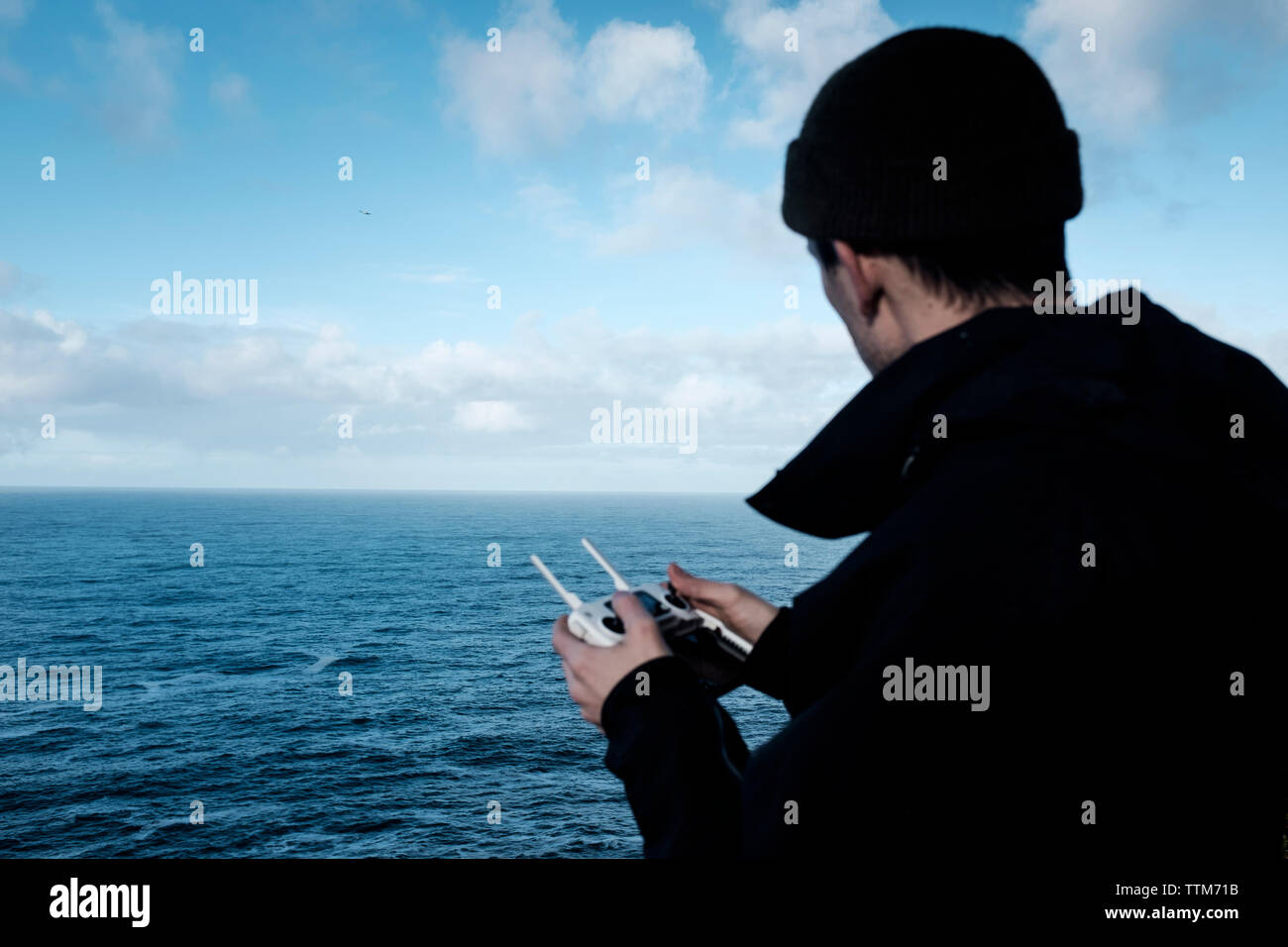 Hiker operating drone remote control against sea Stock Photo