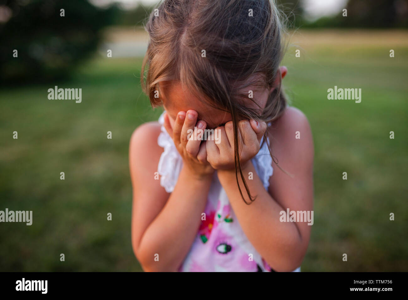 Close-up of girl covering face while crying outdoors Stock Photo