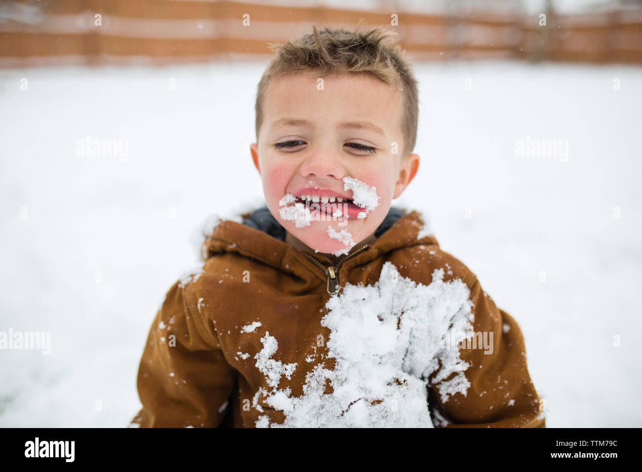 Cute boy sticking out tongue at snow covered field Stock Photo