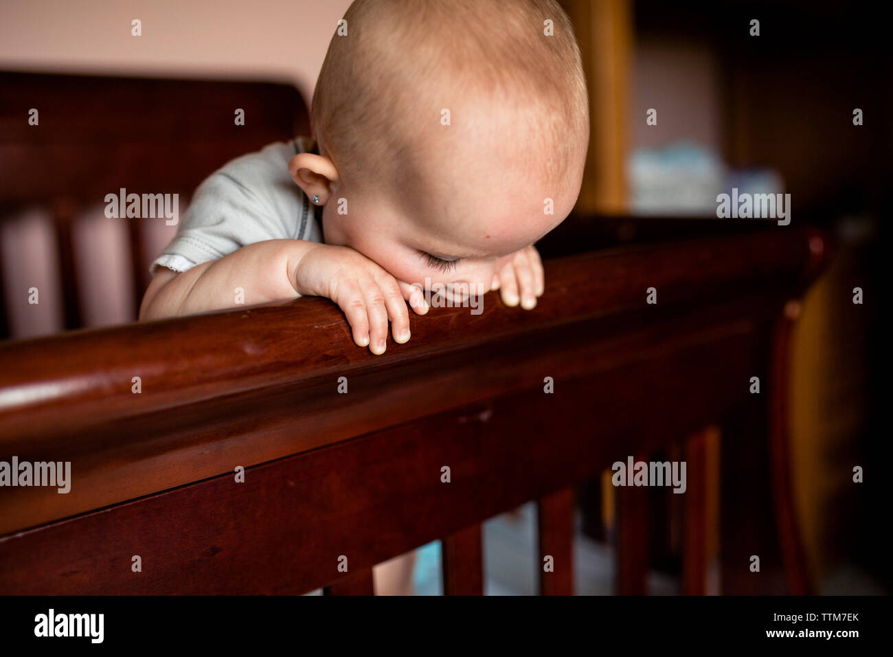 Baby girl biting wooden crib at home Stock Photo Alamy