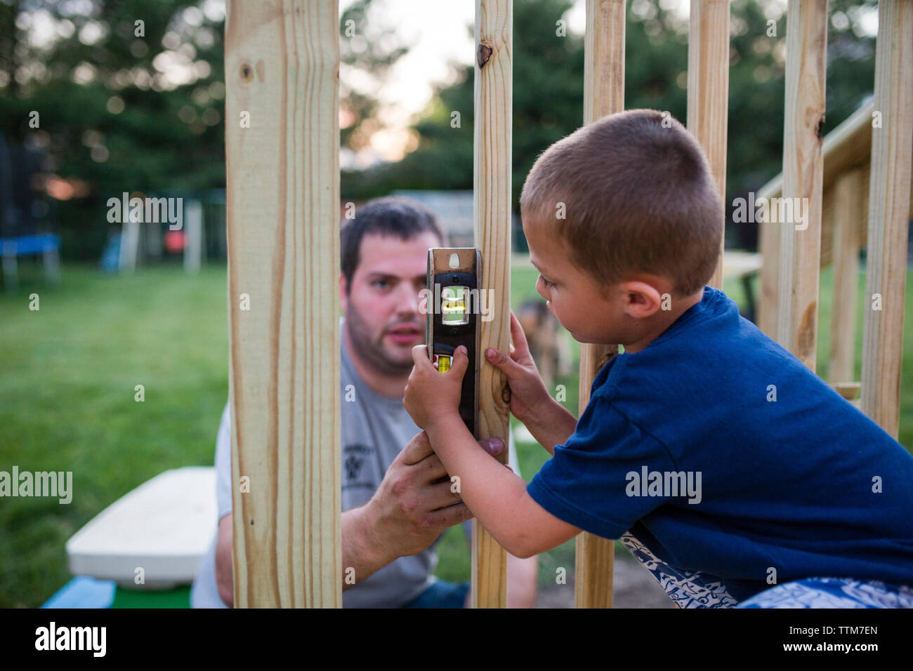 Father teaching son to use spirit level on wooden frame at yard Stock Photo