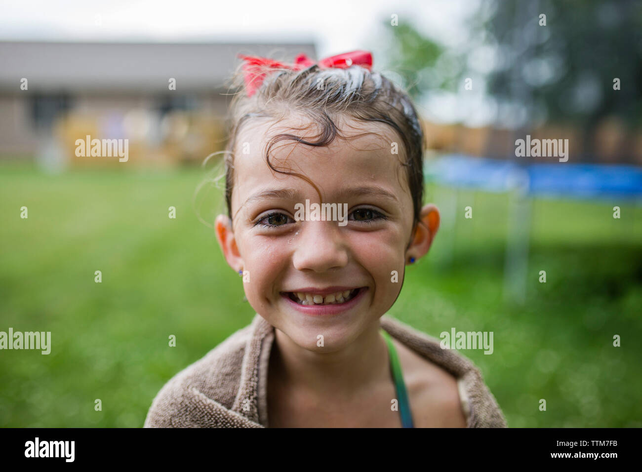 Portrait of happy girl wrapped in towel at yard Stock Photo - Alamy