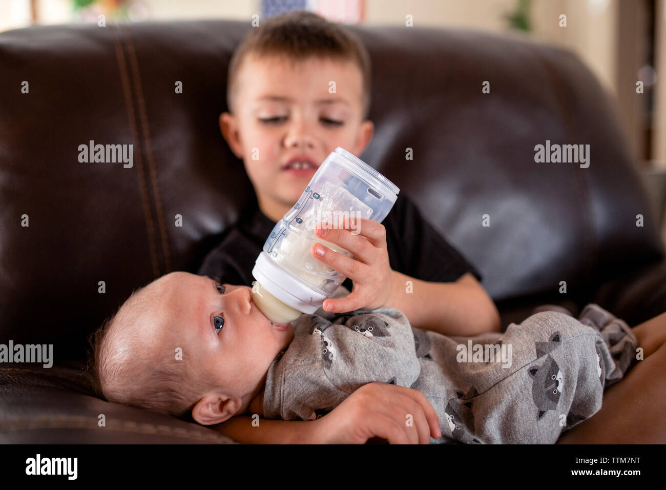 https://c8.alamy.com/comp/TTM7NT/boy-feeding-milk-to-brother-from-baby-bottle-while-sitting-on-sofa-at-home-TTM7NT.jpg