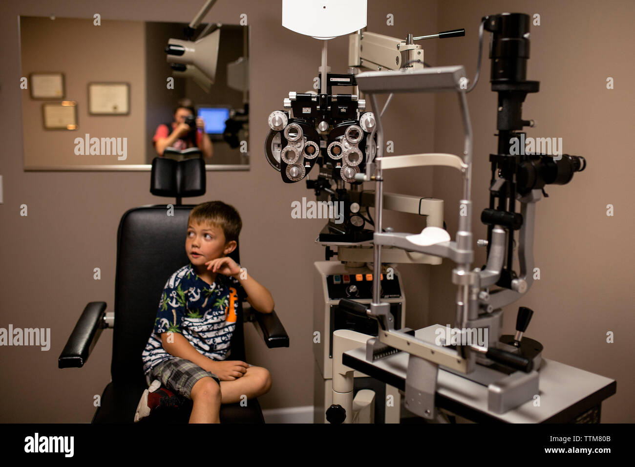 Young boy nervous at the eye doctor with mother Stock Photo