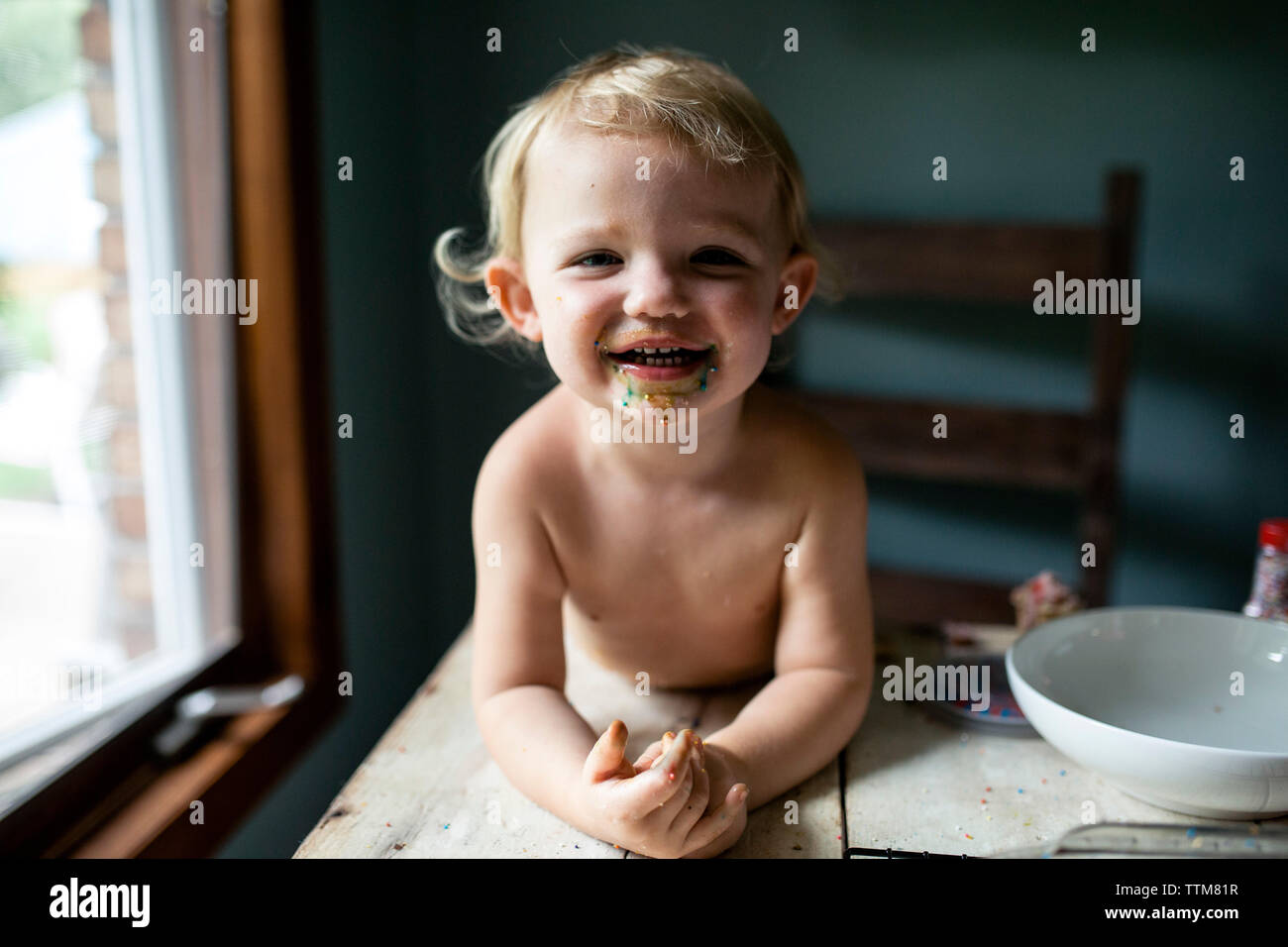 Toddler girl laughing with messy face after colorful sweet treat Stock Photo