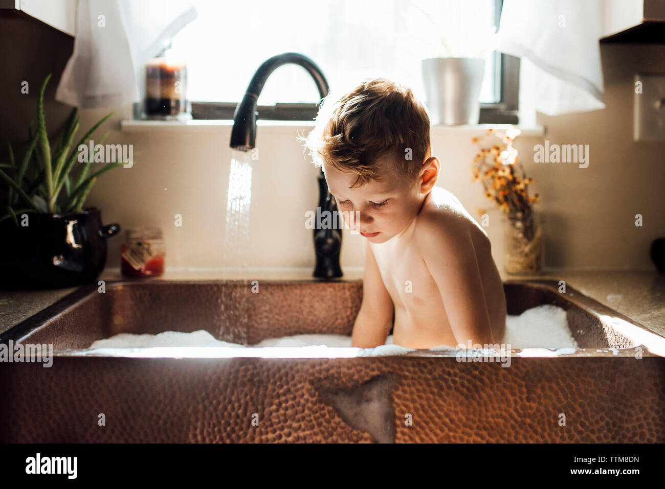 Shirtless boy taking bath while sitting in sink at home Stock Photo Alamy