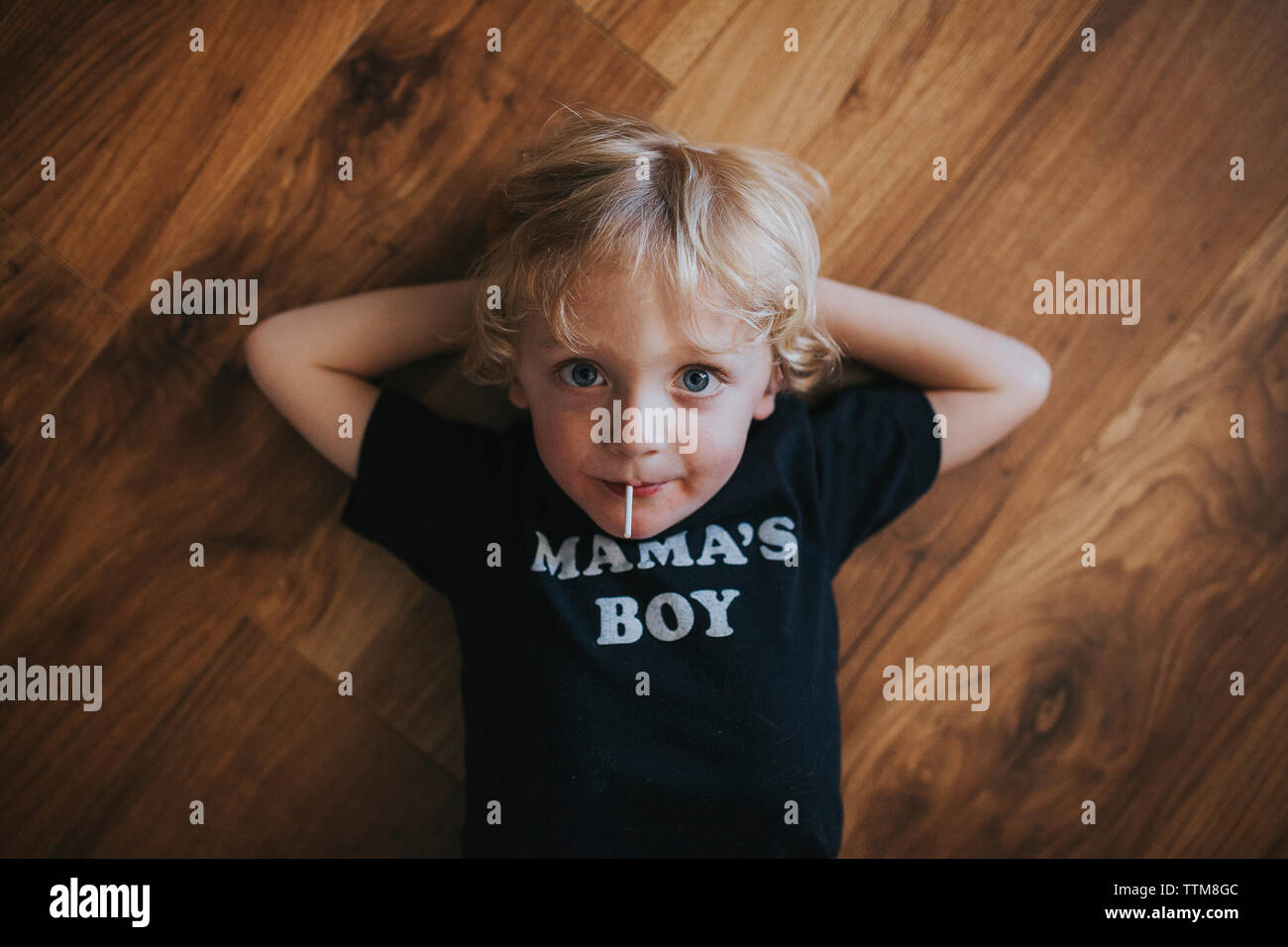 Portrait of boy eating lollipop while lying on floor at home Stock Photo