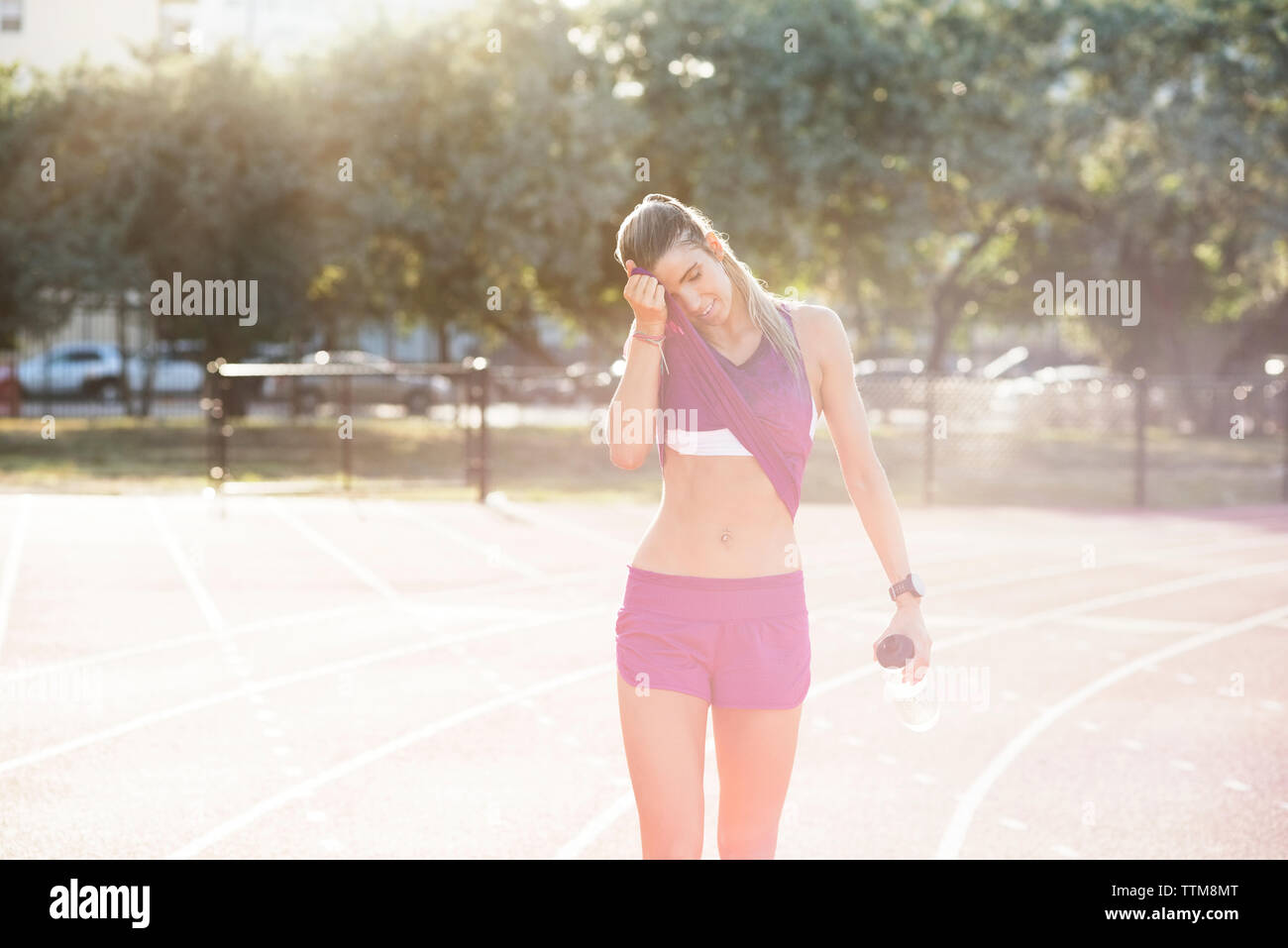 Tired female athlete wiping sweat on field Stock Photo