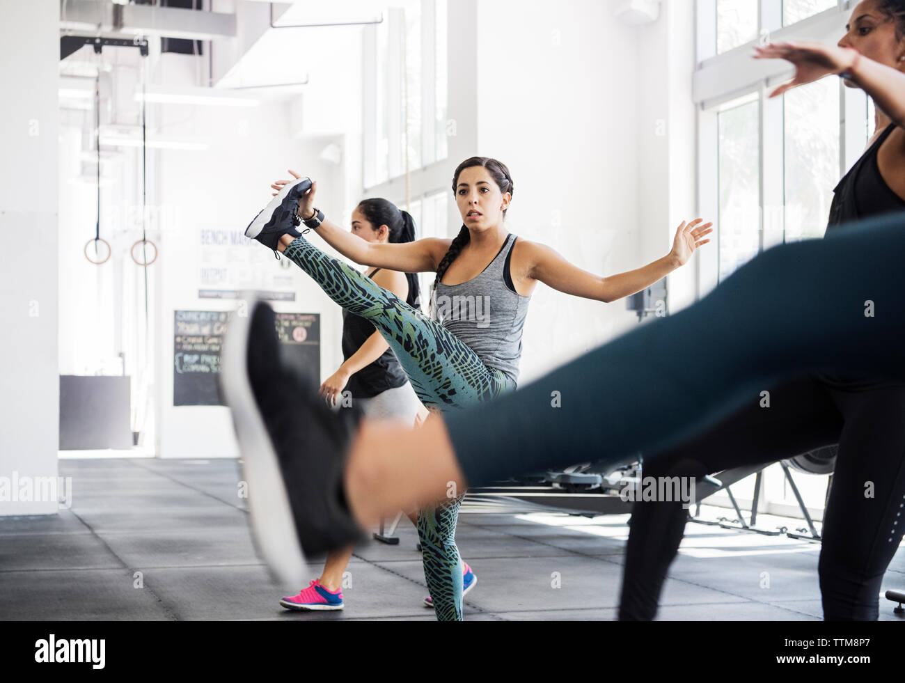Female athletes stretching legs while exercising in crossfit gym Stock Photo