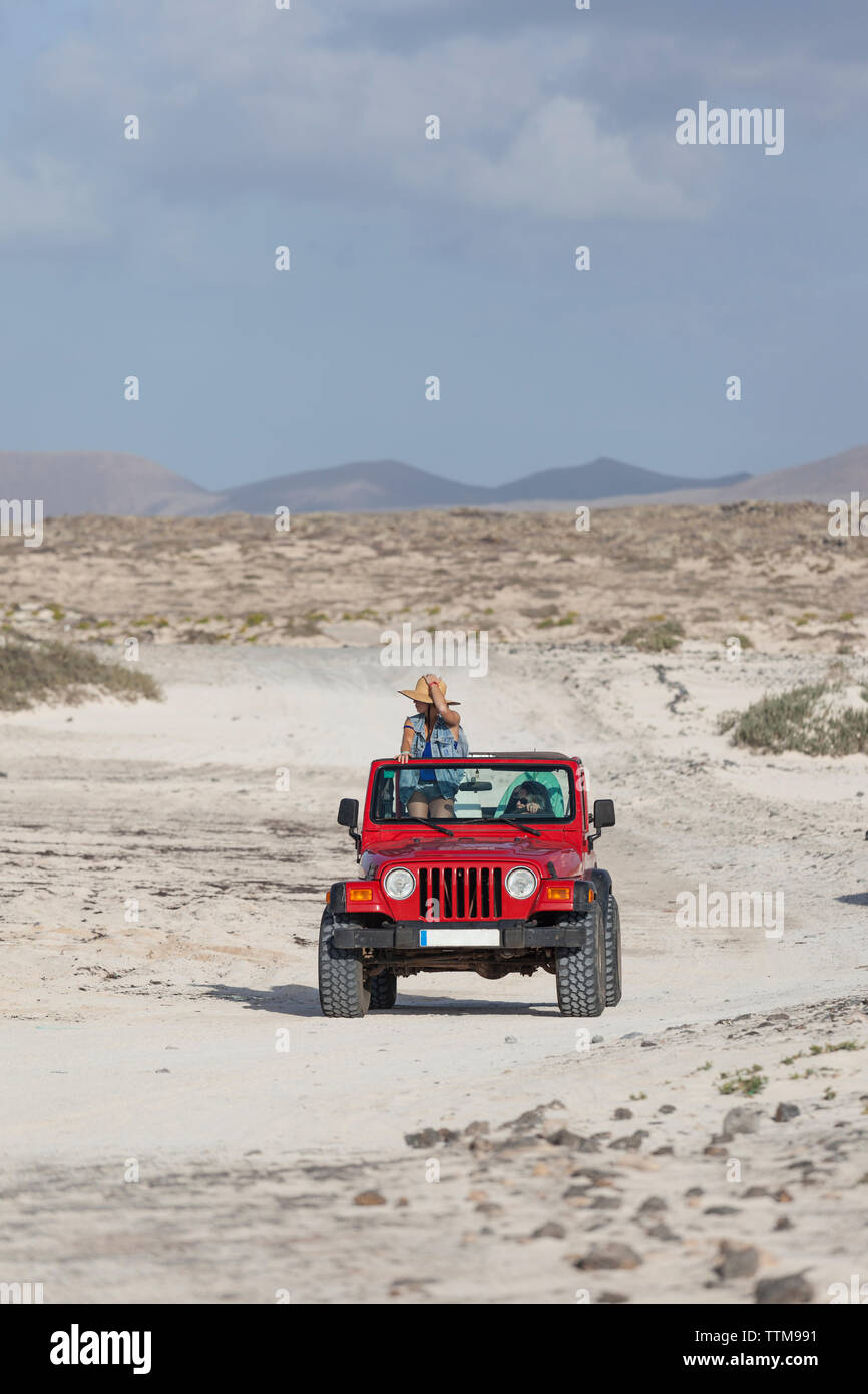 Two surfer girls  on their cabrio 4x4 jeep in a desert landscape Stock Photo