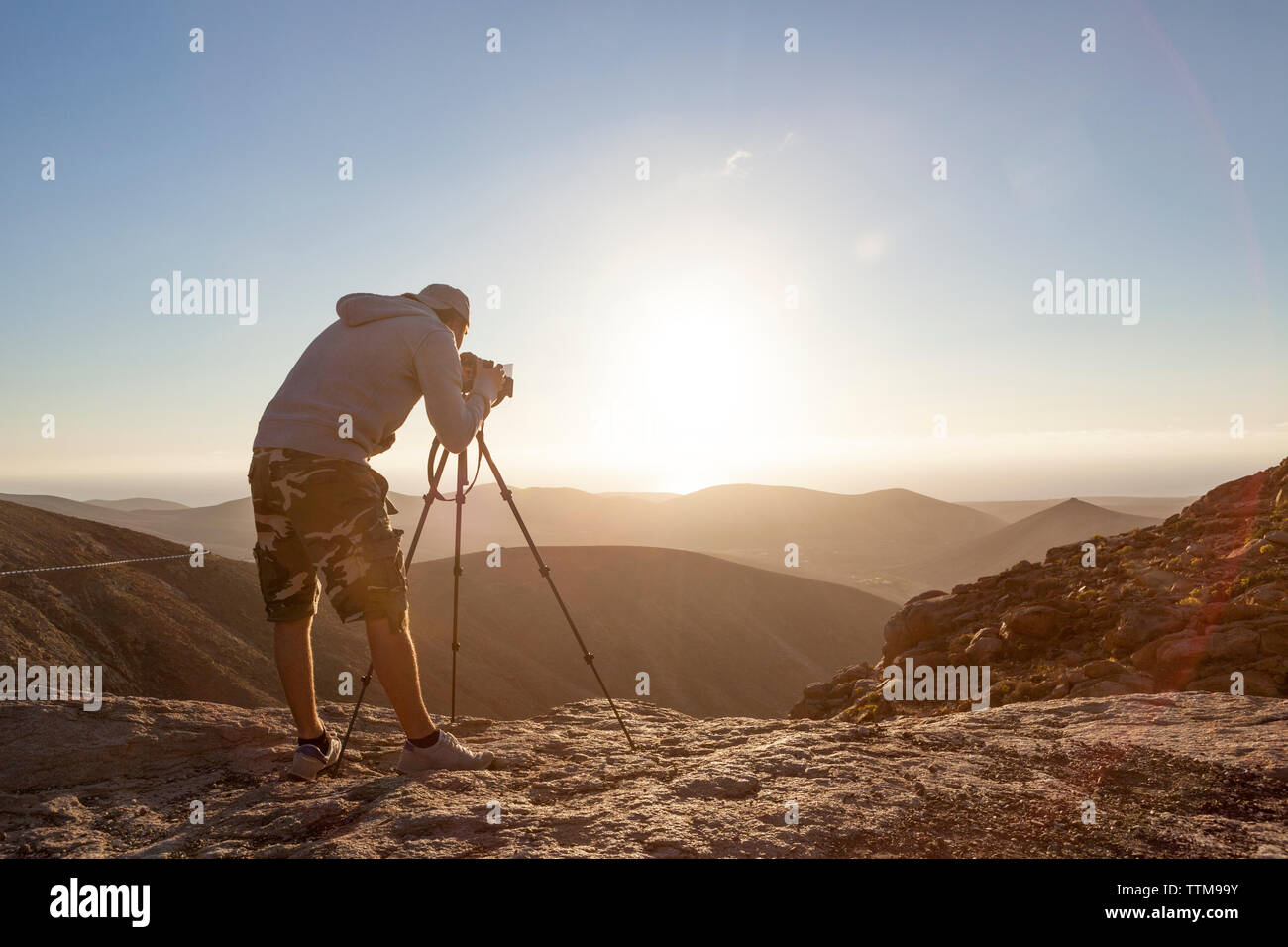 20 30 yrs old photographer taking picture at sunset from a high point Stock Photo