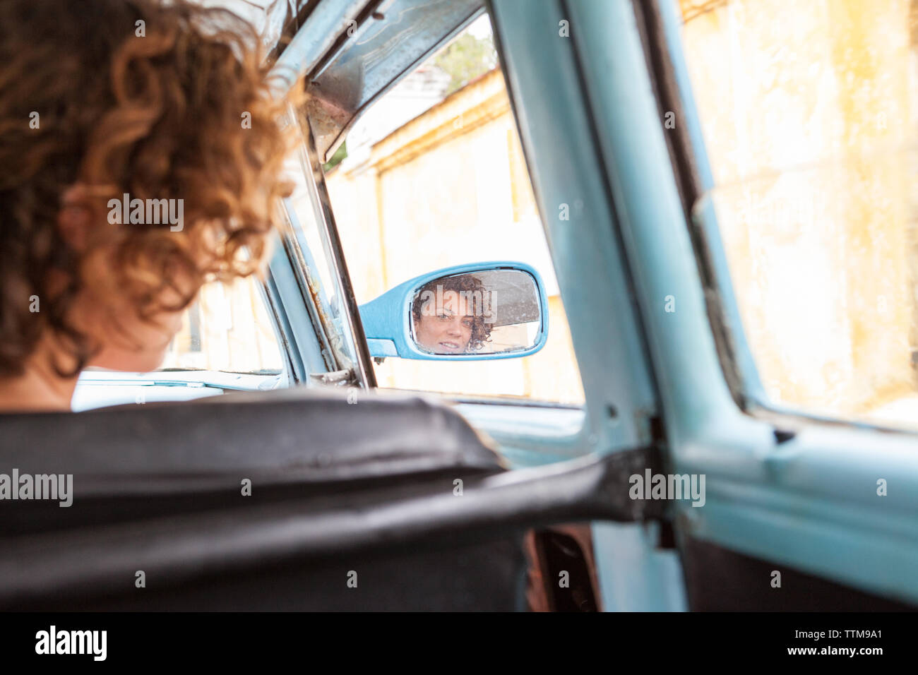 Western girl's face reflected in the wing mirror of vintage car, Cuba Stock Photo