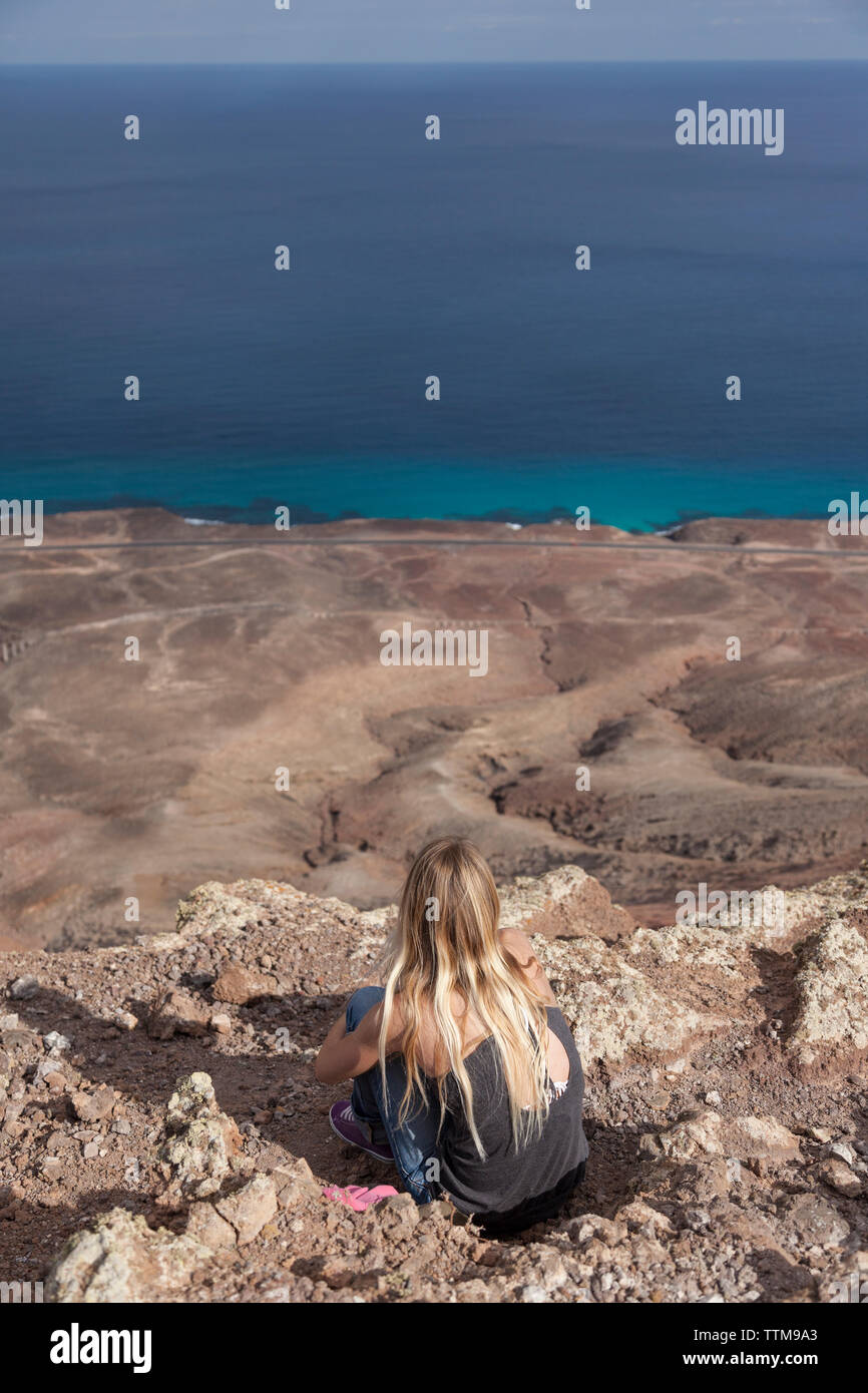 20 30 yrs old blonde girl admiring panorama from summit of a volcano Stock Photo
