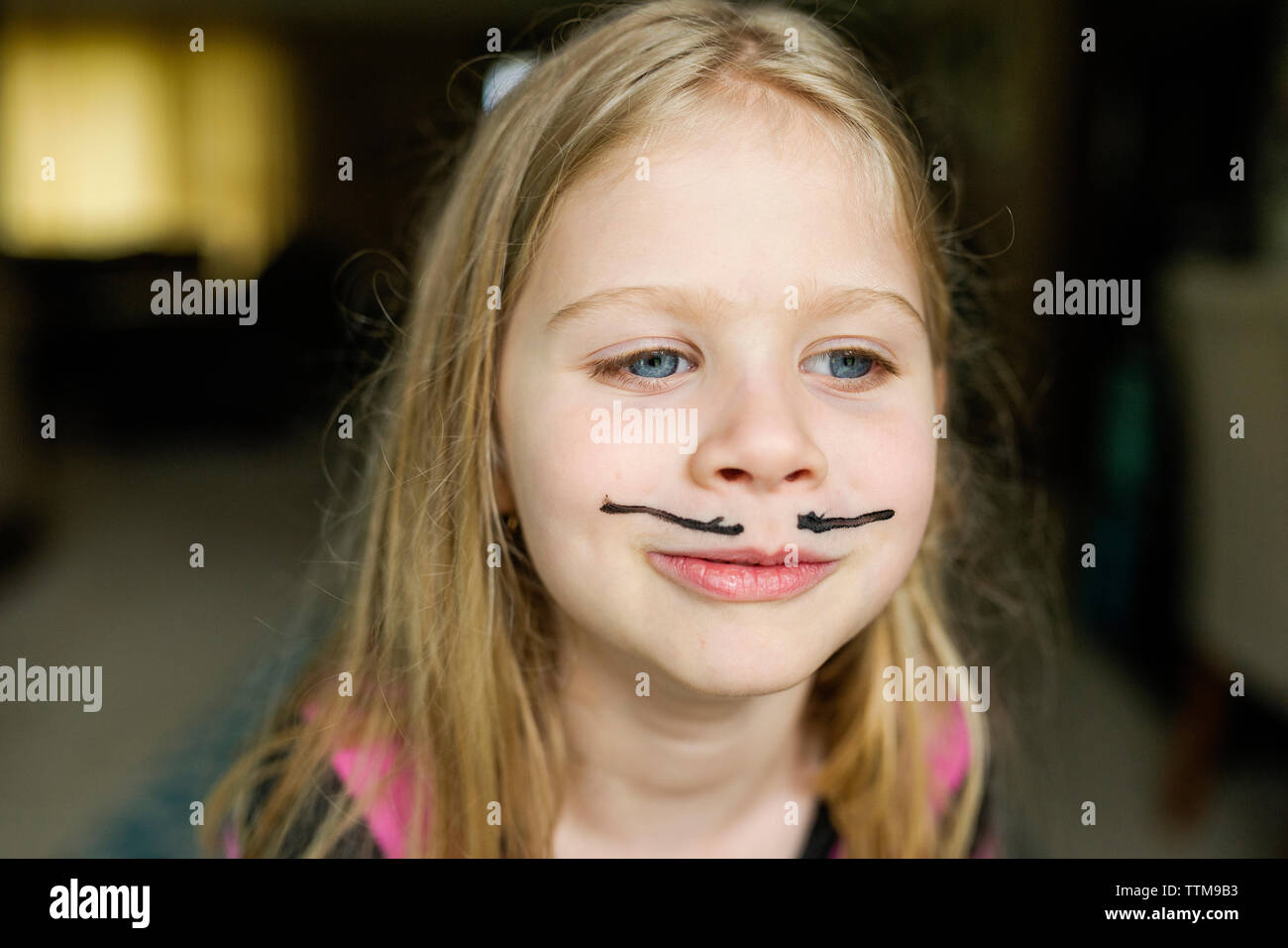 Girl with mustache face paint at home Stock Photo