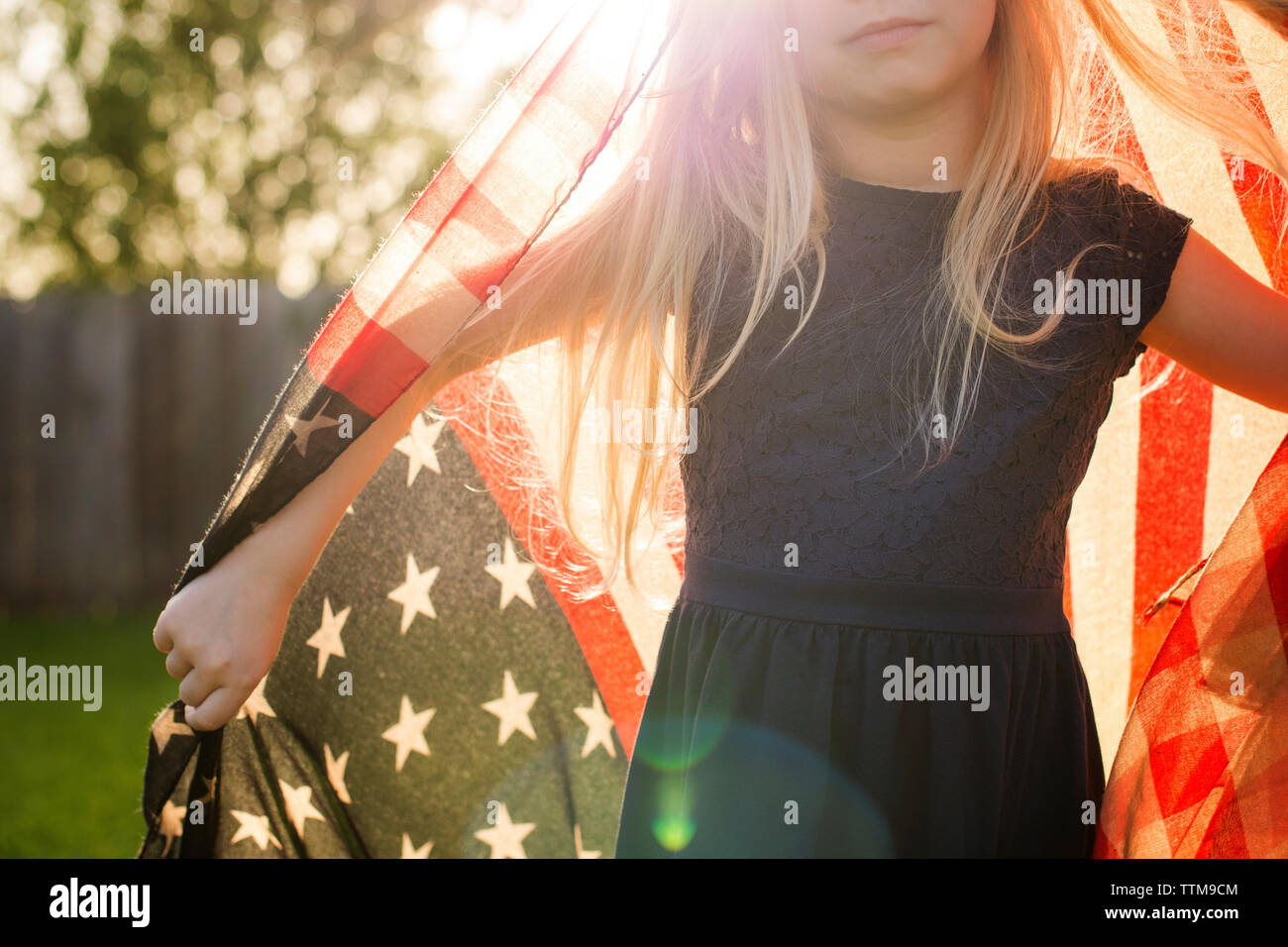 Midsection of girl with American flag in backyard Stock Photo