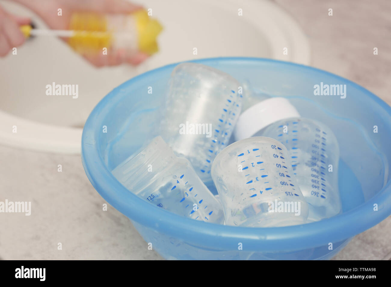 Woman hands washing baby bottles in plastic blue basin Stock Photo Alamy