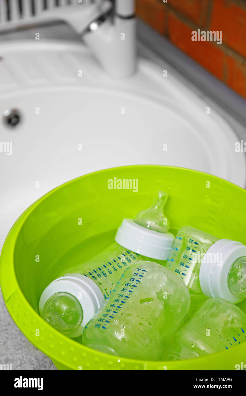 Sterilizing baby bottles in plastic green basin Stock Photo Alamy