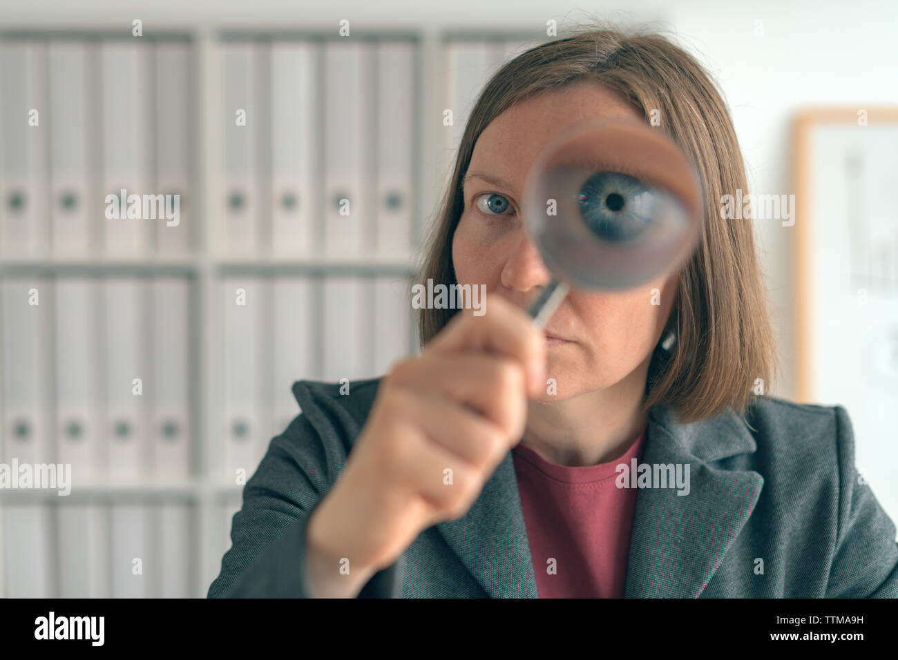 Businesswoman with magnifying glass doing business financial auditing, examination and evaluation of financial statements. Stock Photo