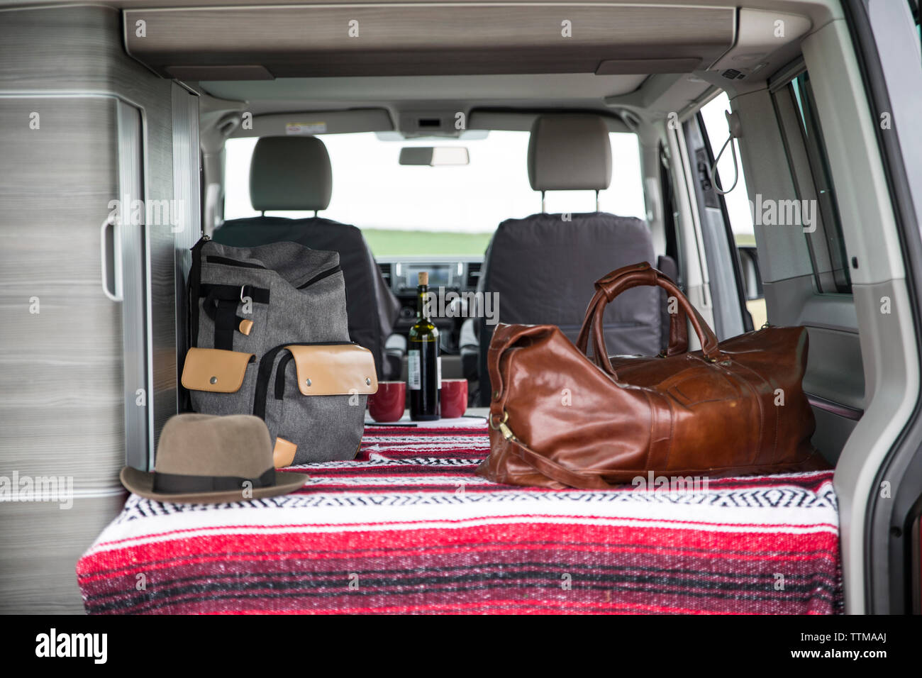 Backpacks with hat and drink in motor home seen through car trunk Stock Photo