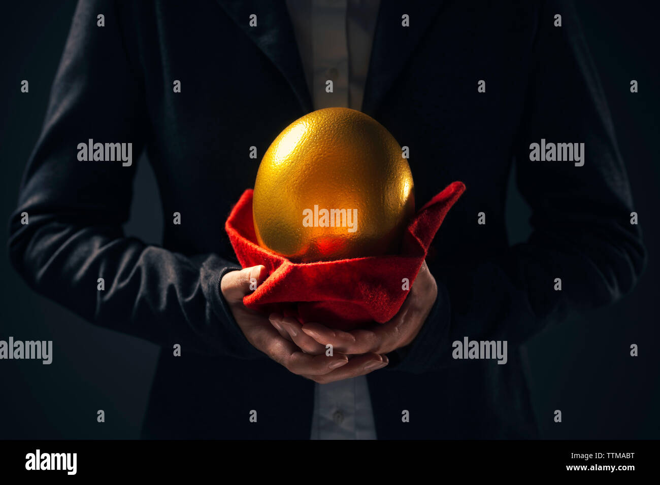 Large golden egg in hands of businesswoman acting as stockholder or investor in business investment Stock Photo
