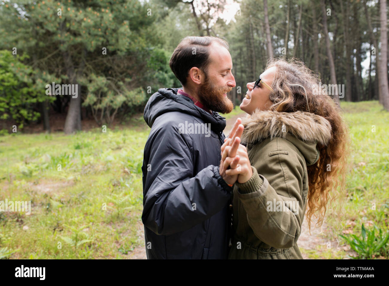 Side view of happy loving couple looking at each other in forest Stock Photo