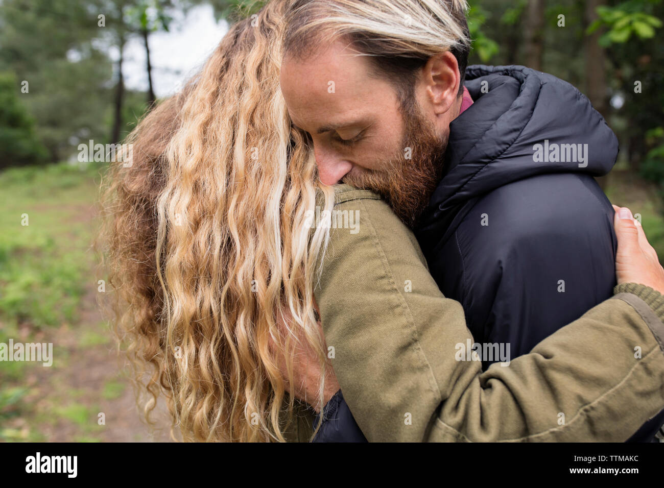Side view of affectionate couple embracing in forest Stock Photo