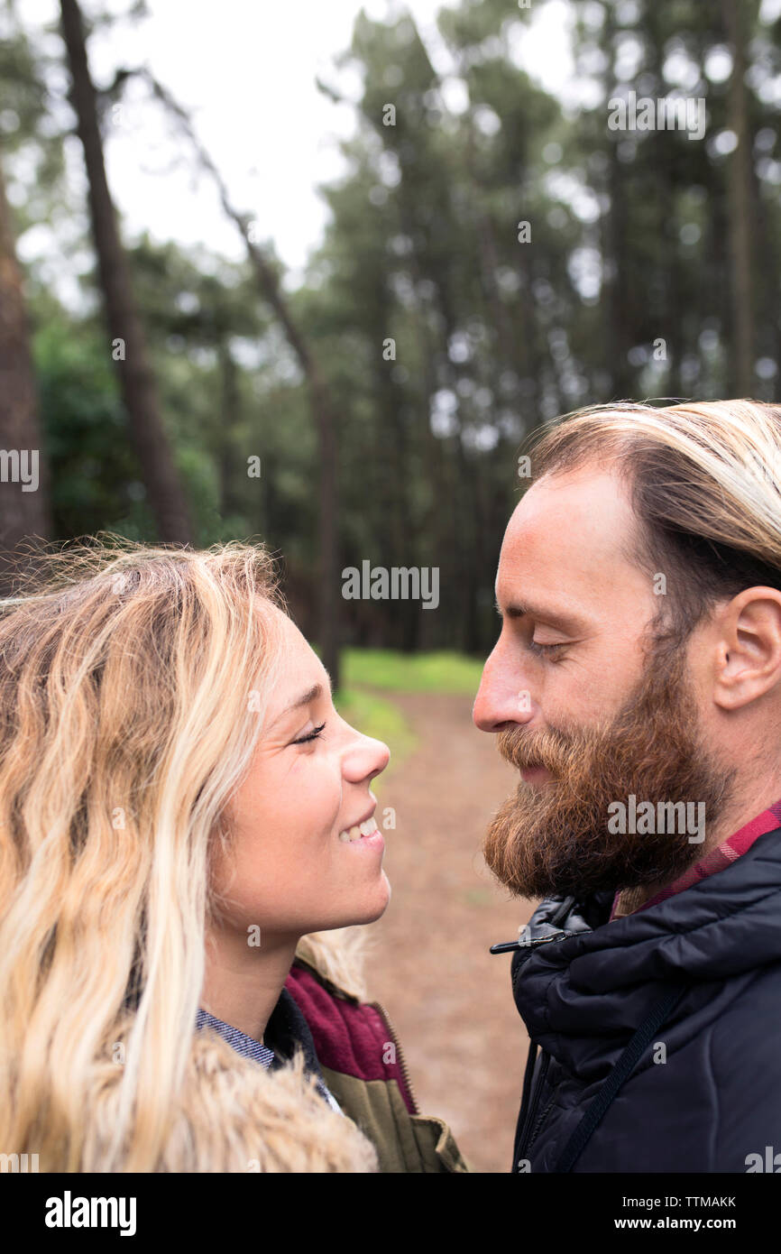 Side view of loving couple looking at each other in forest Stock Photo
