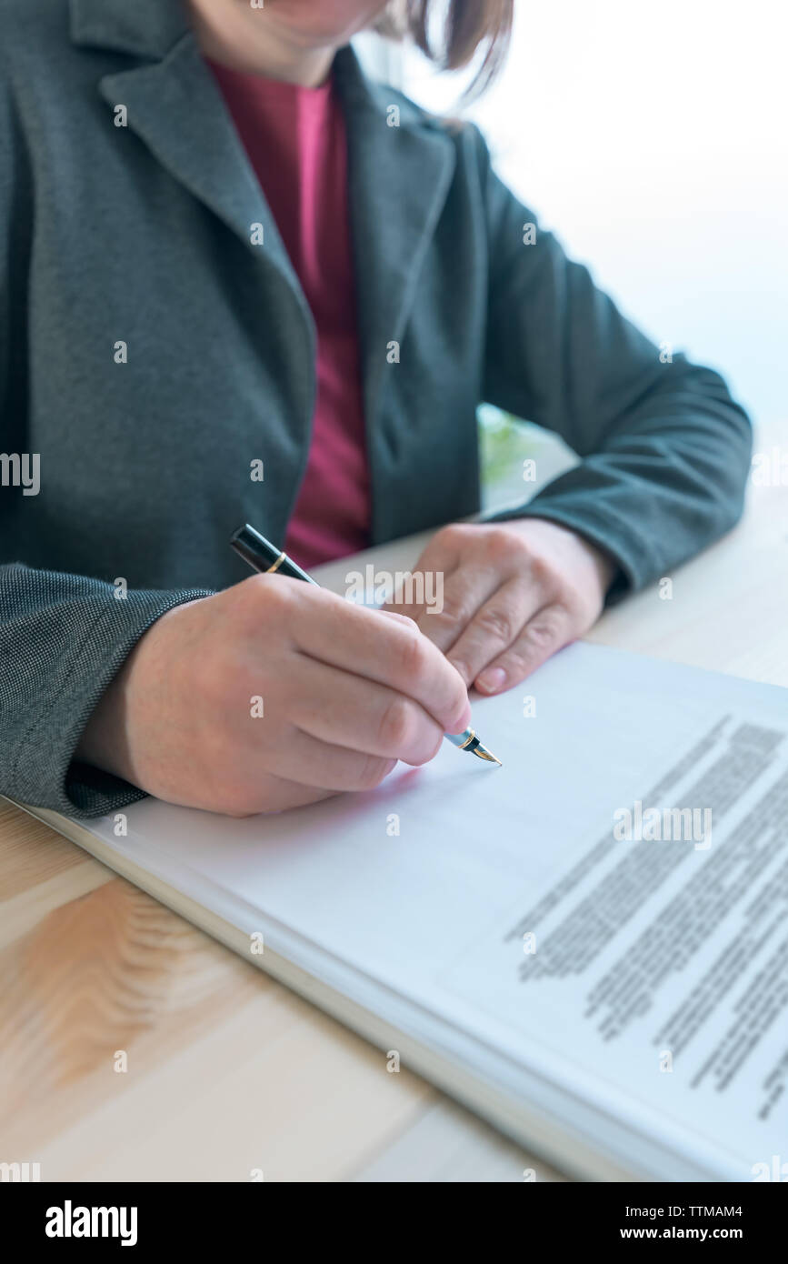 Businesswoman signing contract and business partnership agreement at office desk Stock Photo