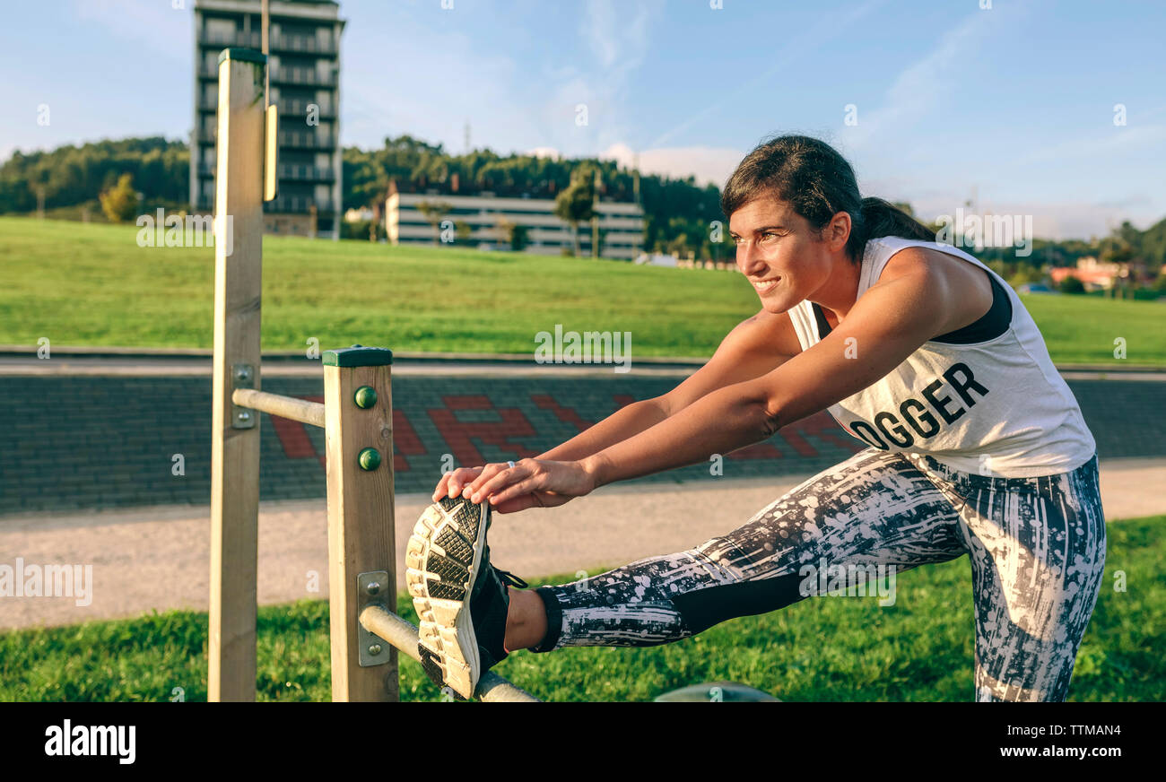 Woman stretching leg while exercising at park Stock Photo