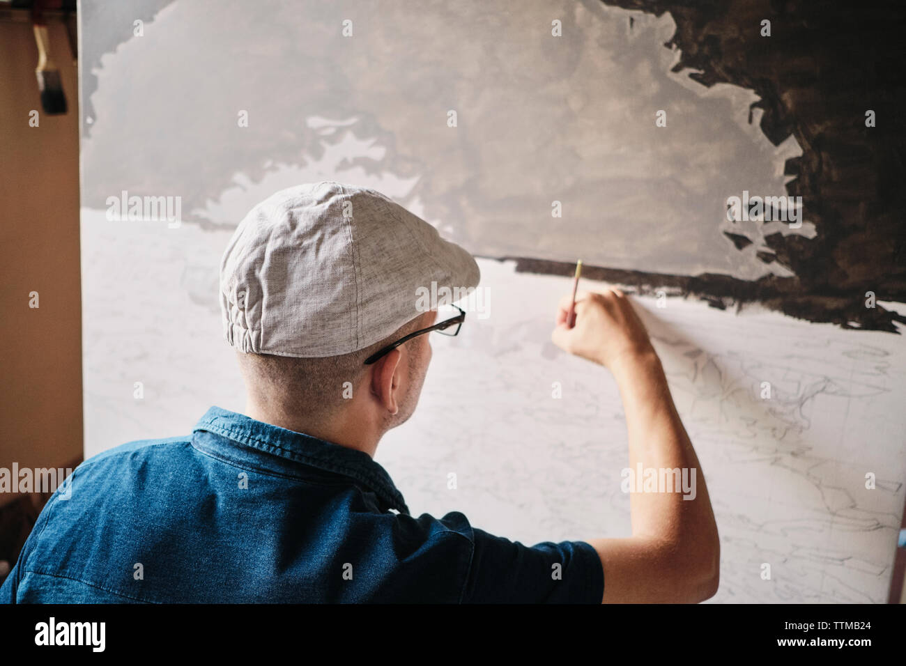Mid adult Cuban artist painting with brush on canvas in his studio Stock Photo
