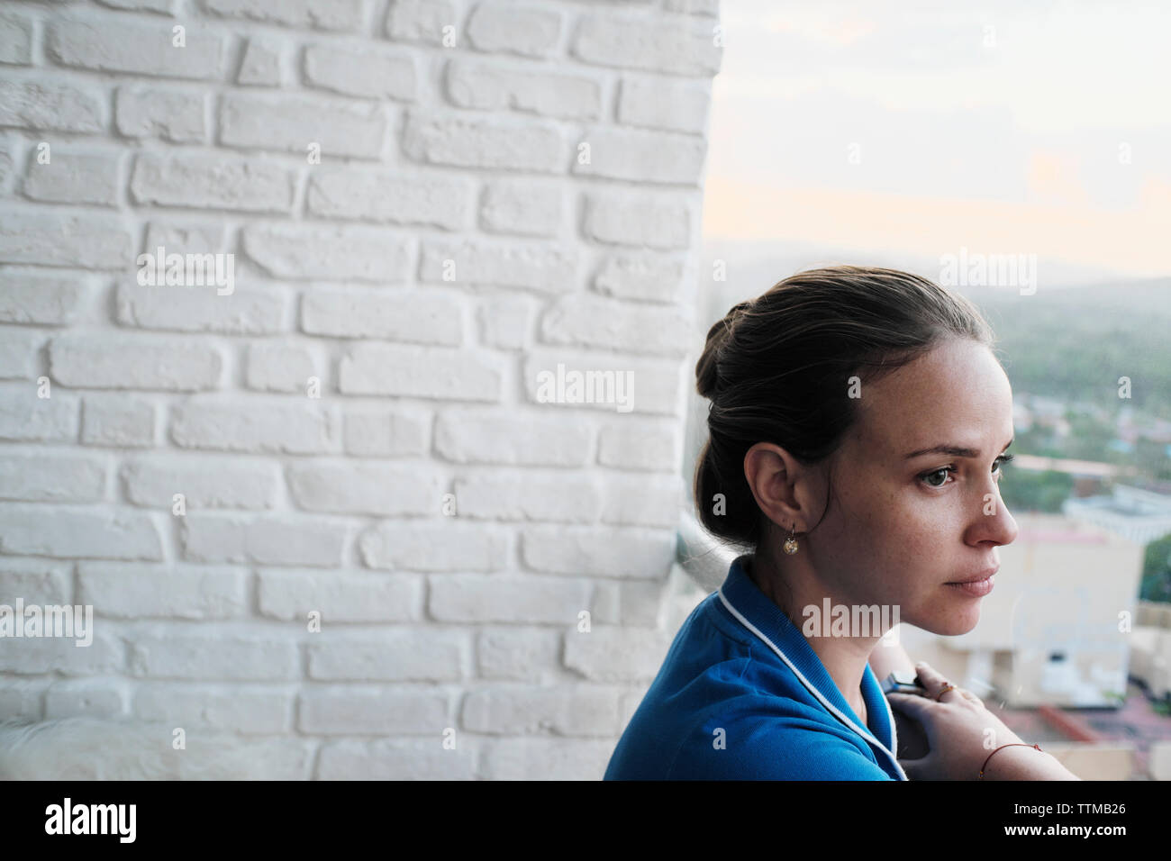 Young Blond Woman Looking Outside Window With Sad Expression Stock Photo