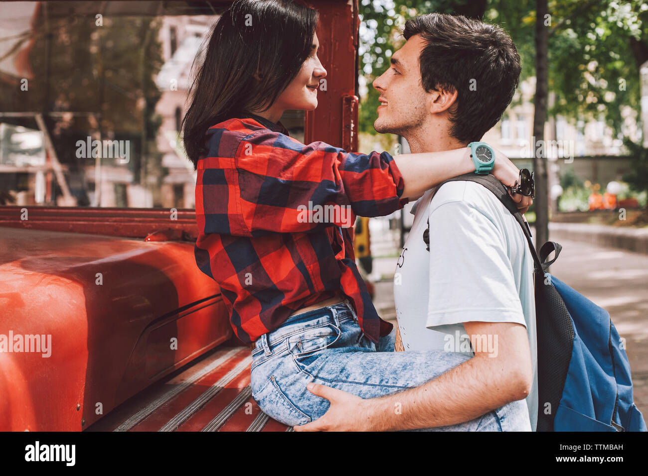 Side view of young couple looking each other face to face in city by vintage bus Stock Photo