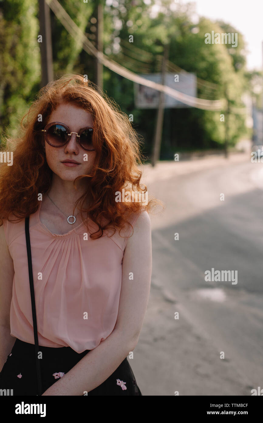 Young woman in sunglasses standing in city street during summer Stock Photo