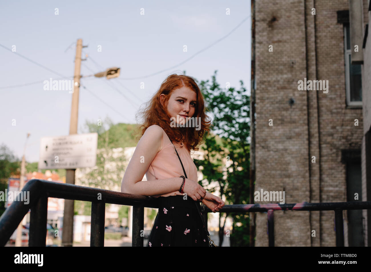 Portrait of young redhead  woman leaning by railing in city Stock Photo
