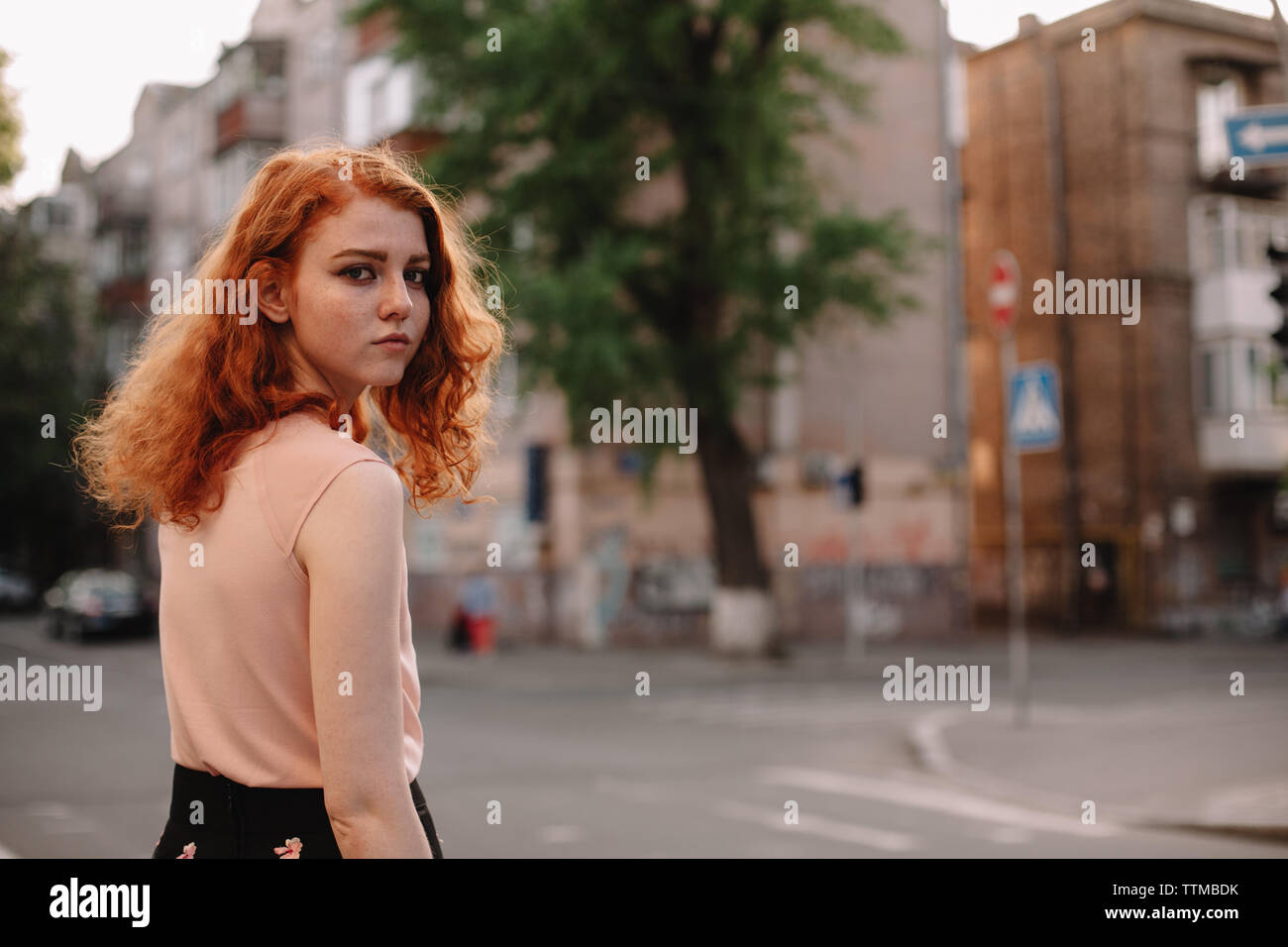 Young redheaded woman walking in city street Stock Photo