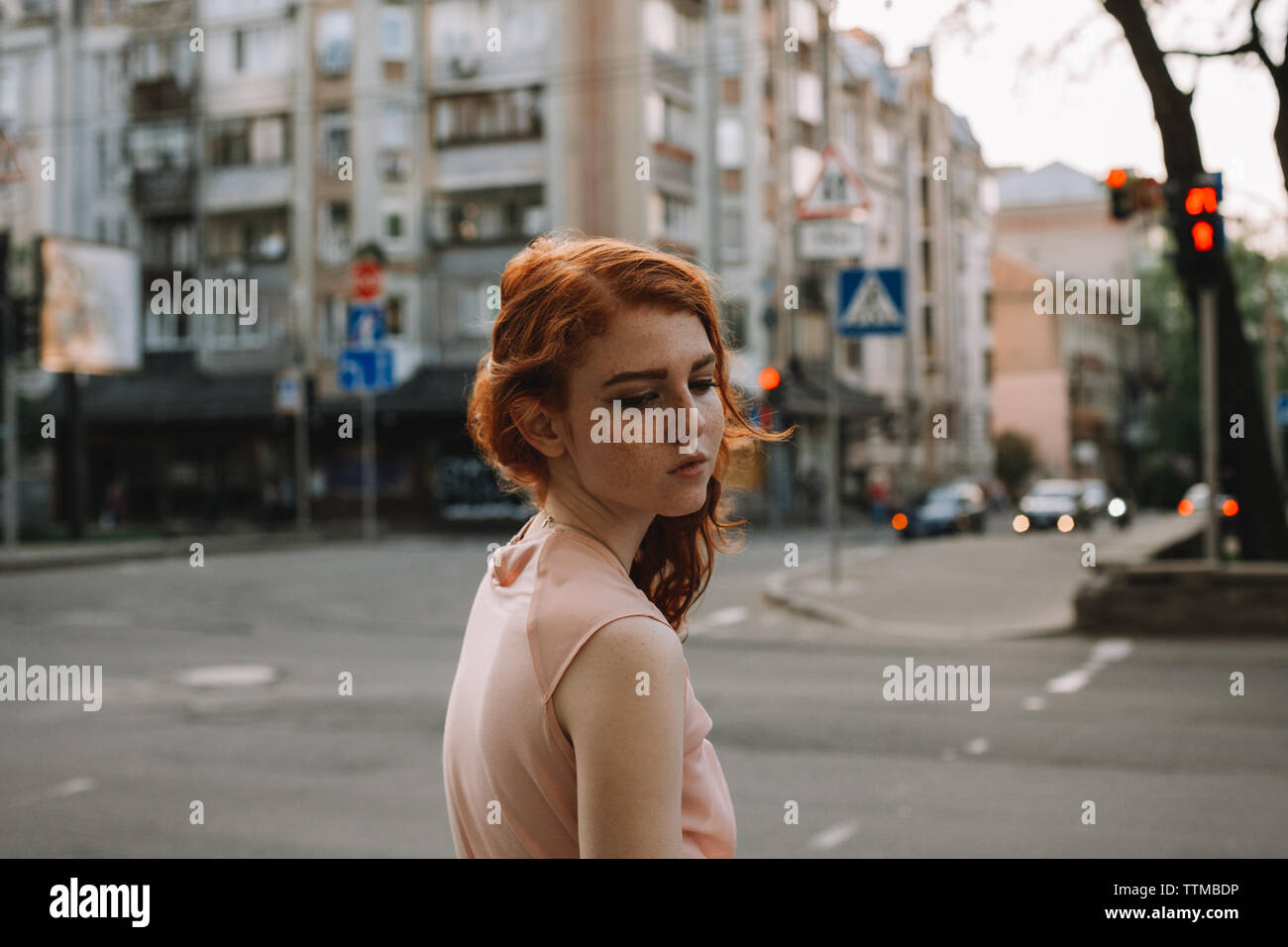 Portrait of young sad woman with freckles standing in city street Stock Photo