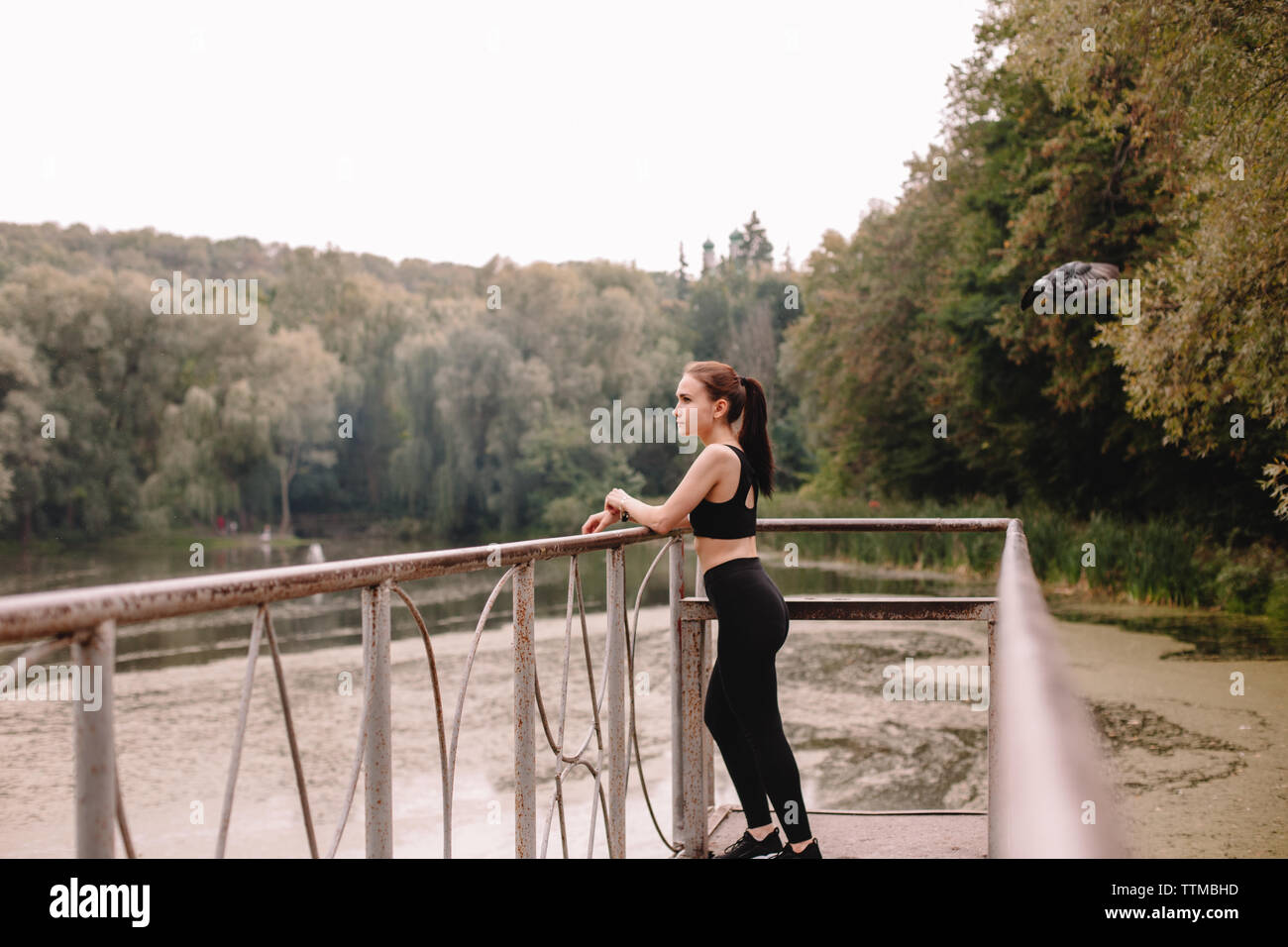 Female jogger standing on pier by lake Stock Photo