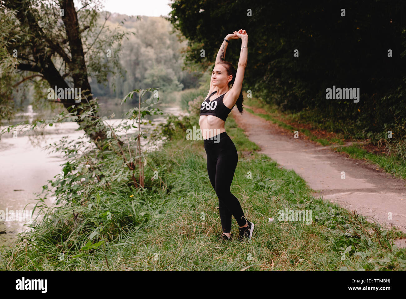 Female jogger exercising by lake in park Stock Photo
