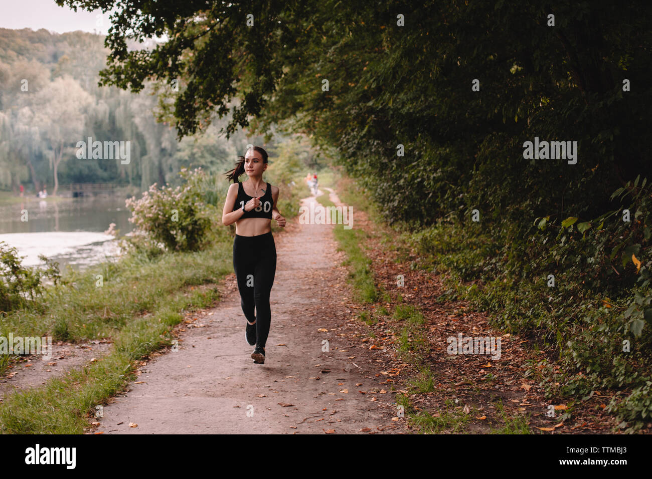 Young determined woman jogging at park Stock Photo