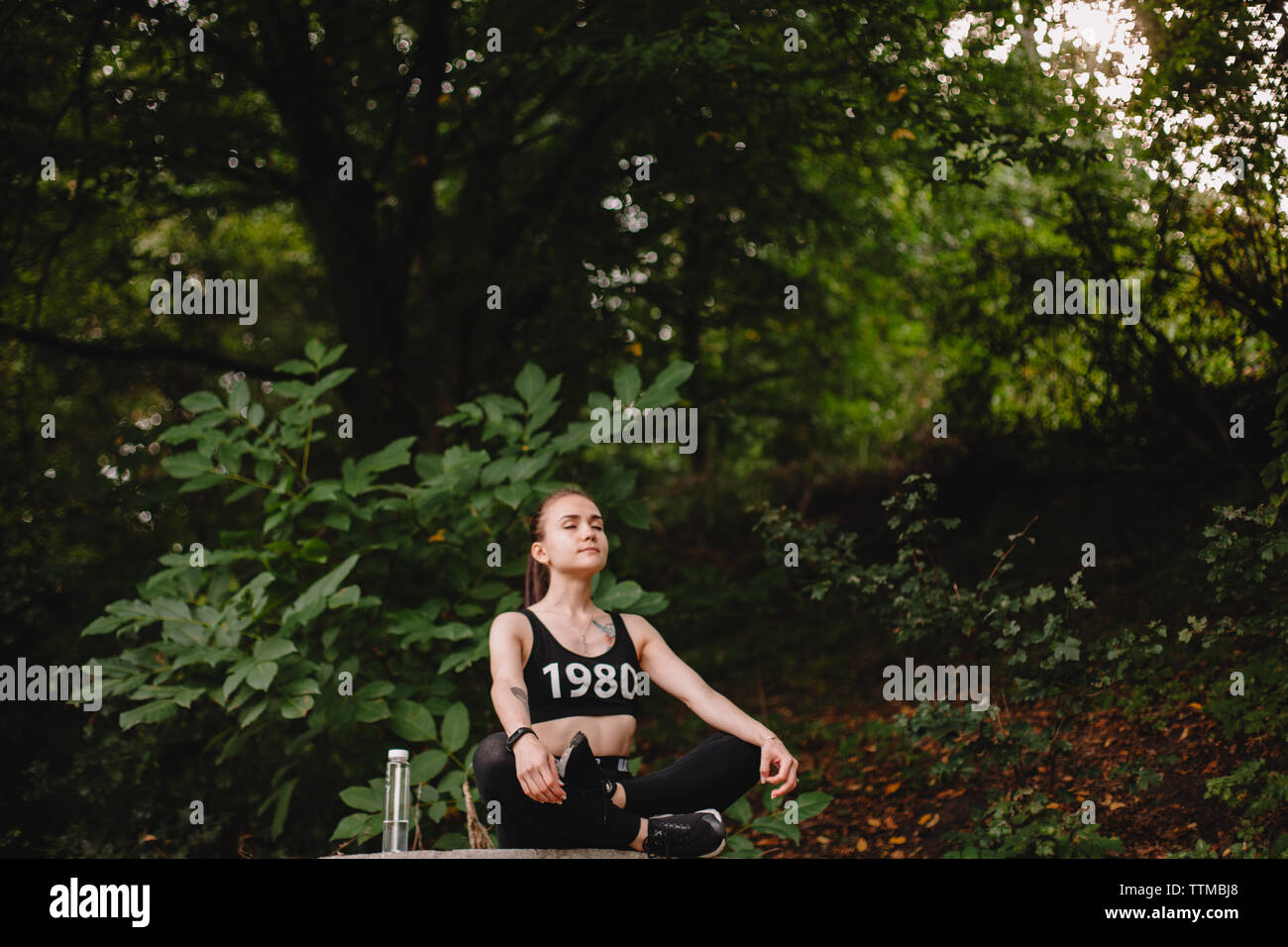 Woman practicing yoga in park against trees Stock Photo