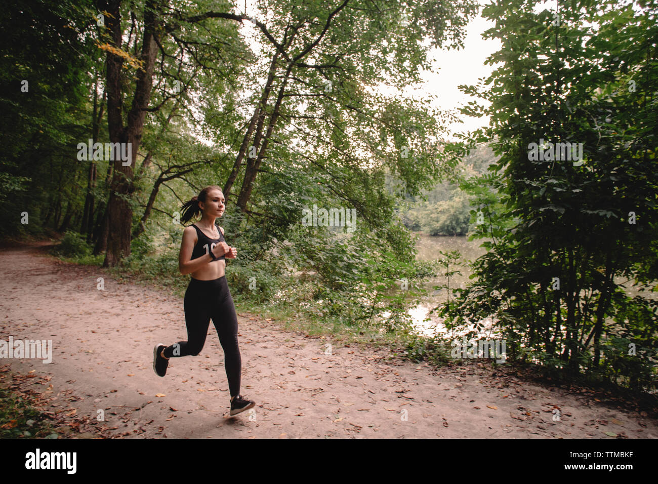 Young woman running at park by lake Stock Photo