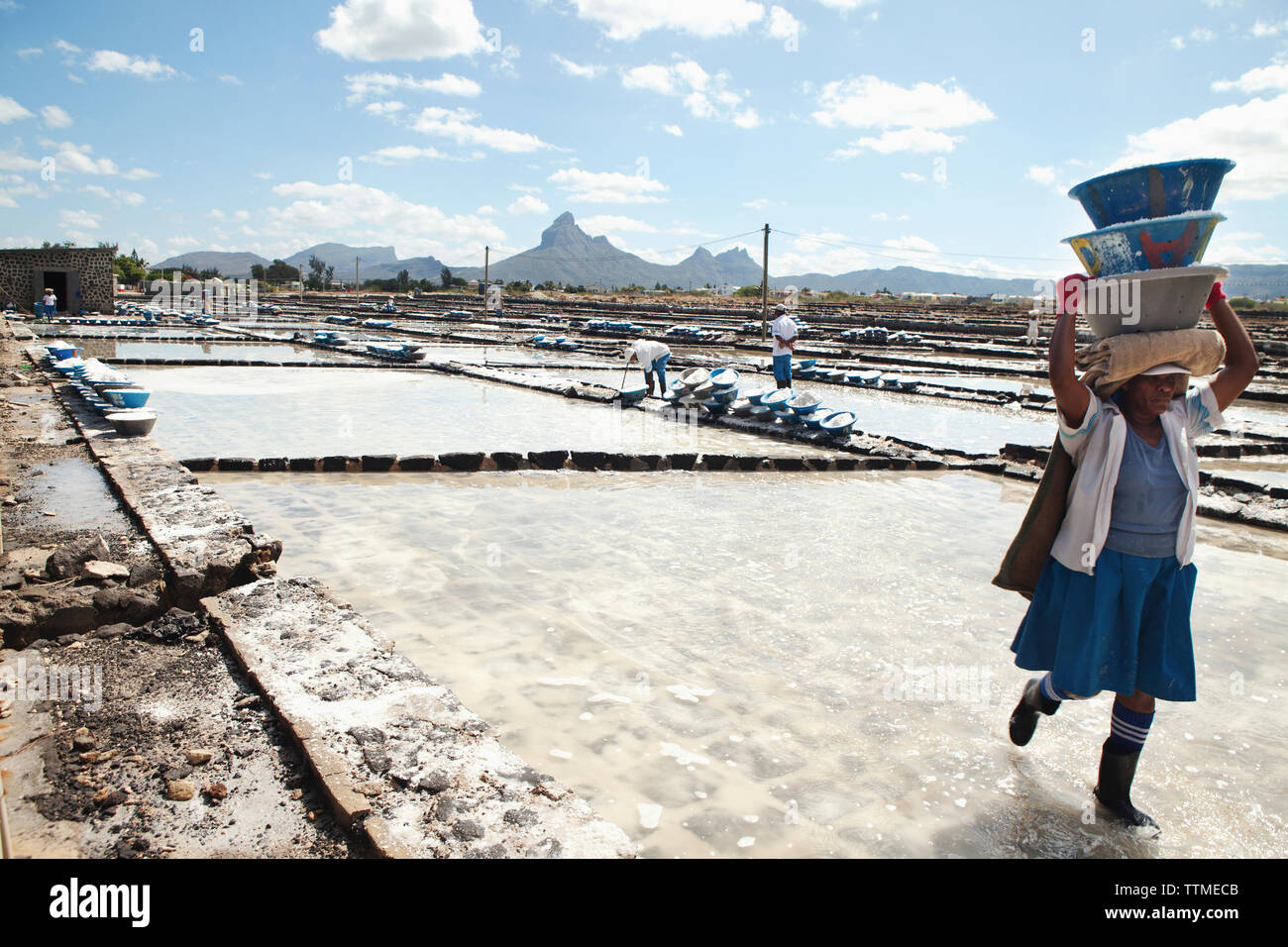 MAURITIUS, Tamarin, women carry heavy loads of salt to a storage facility where it is stored and prepared for transportation, Tamarin Salt Pans Stock Photo