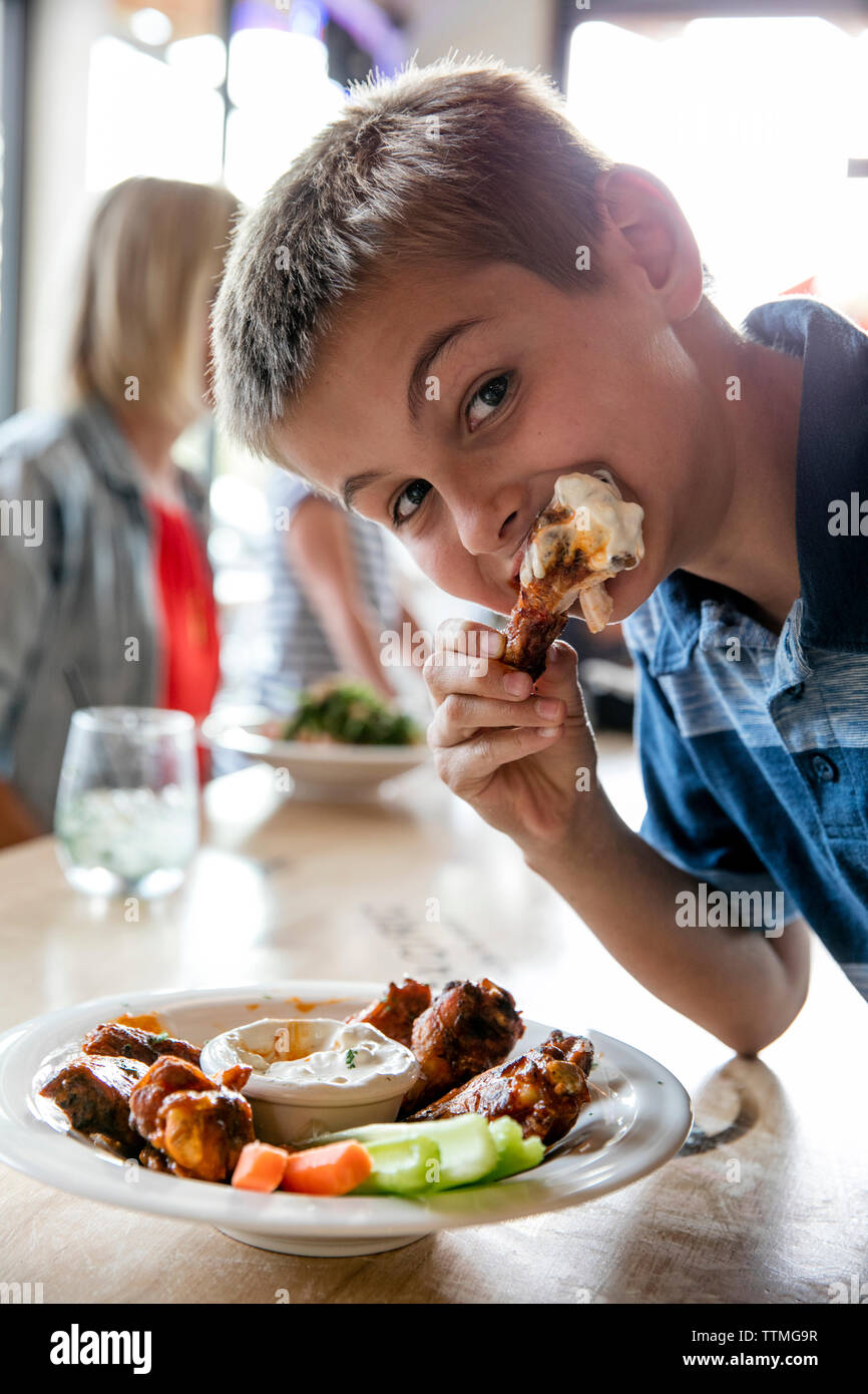 USA, Oregon, Bend, Pacific Pizza and Brew, boy tasting hot wings Stock Photo